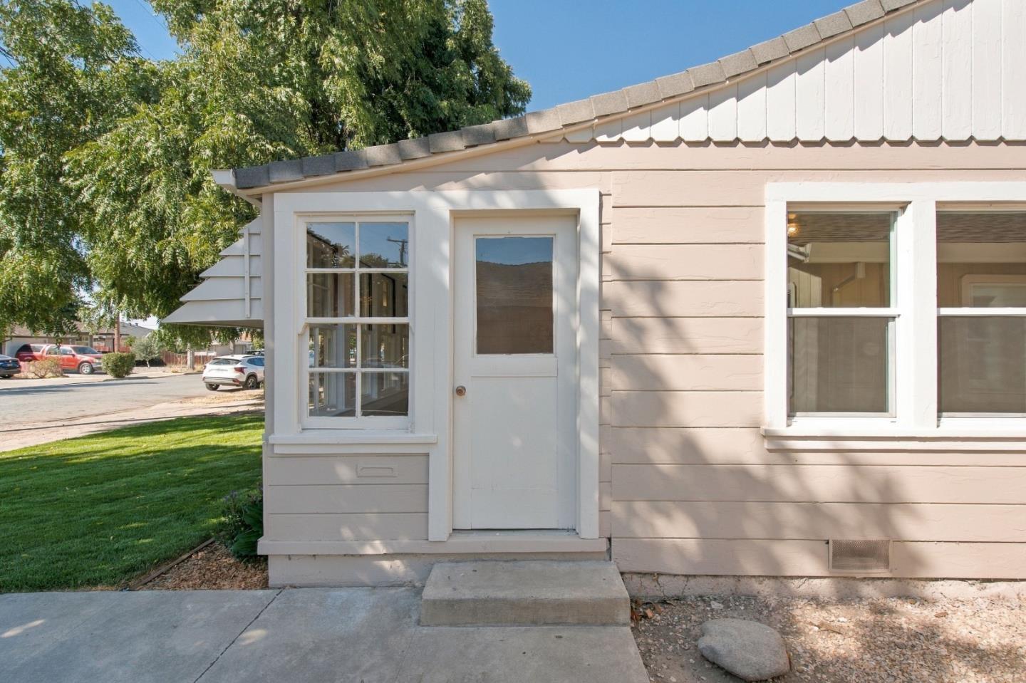Single-story home with beige siding, white trim, and a centered front door beside a green lawn.
