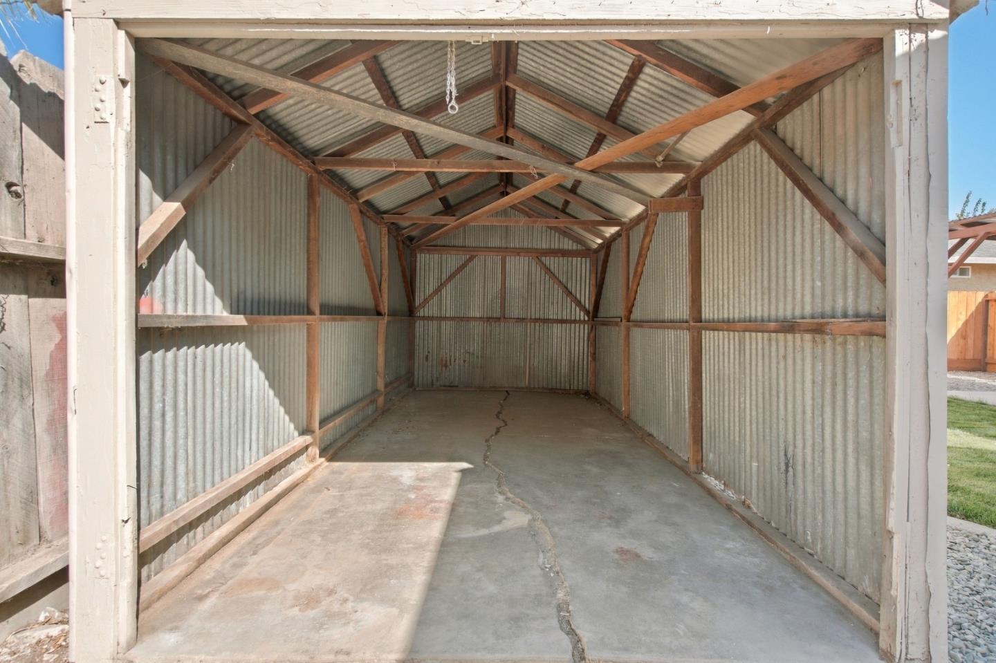 Metal-sided garage interior with exposed timber framing and a cracked concrete floor.