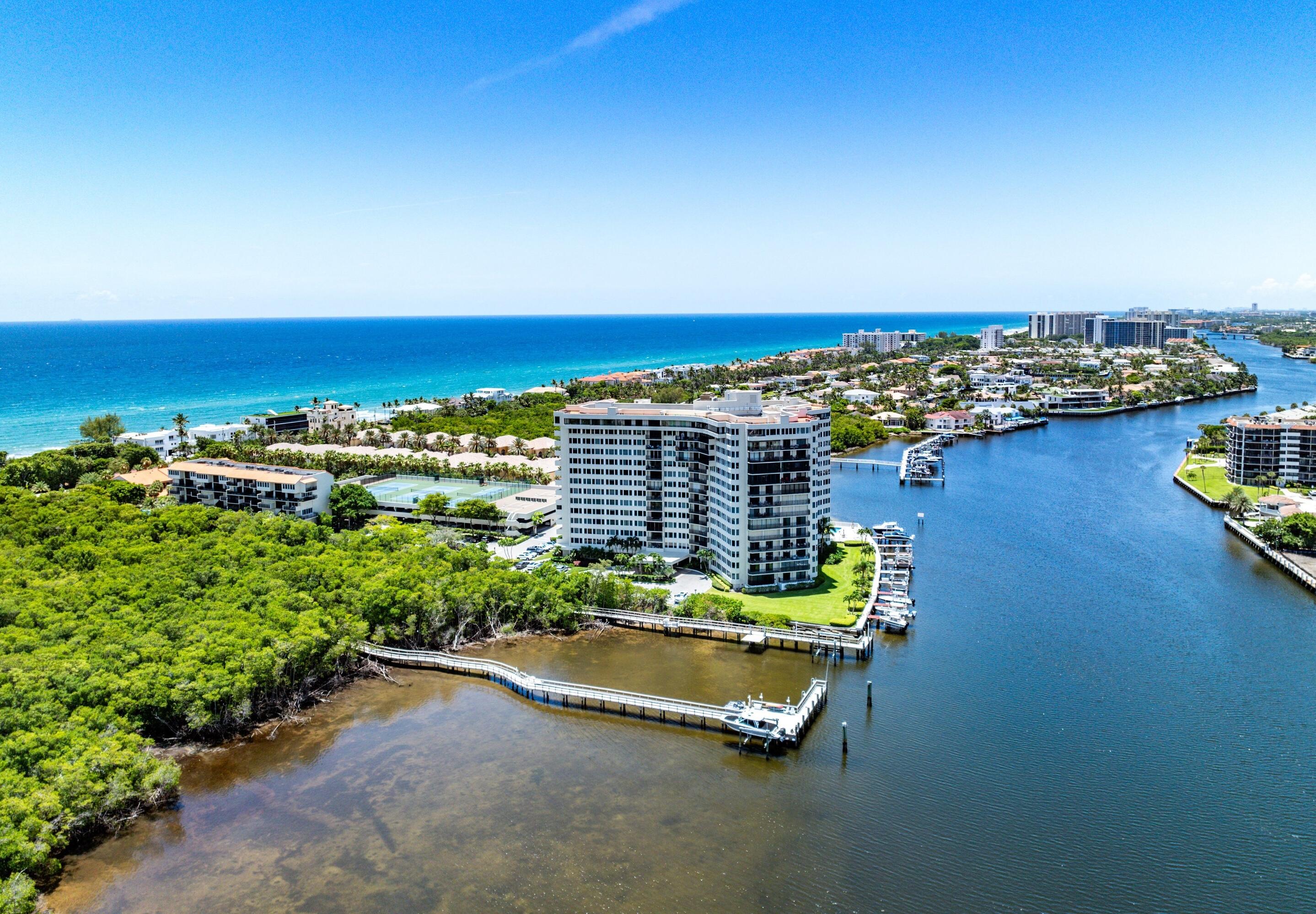 Aerial view of a waterfront condominium beside a marina, with the Atlantic shoreline in the distance.