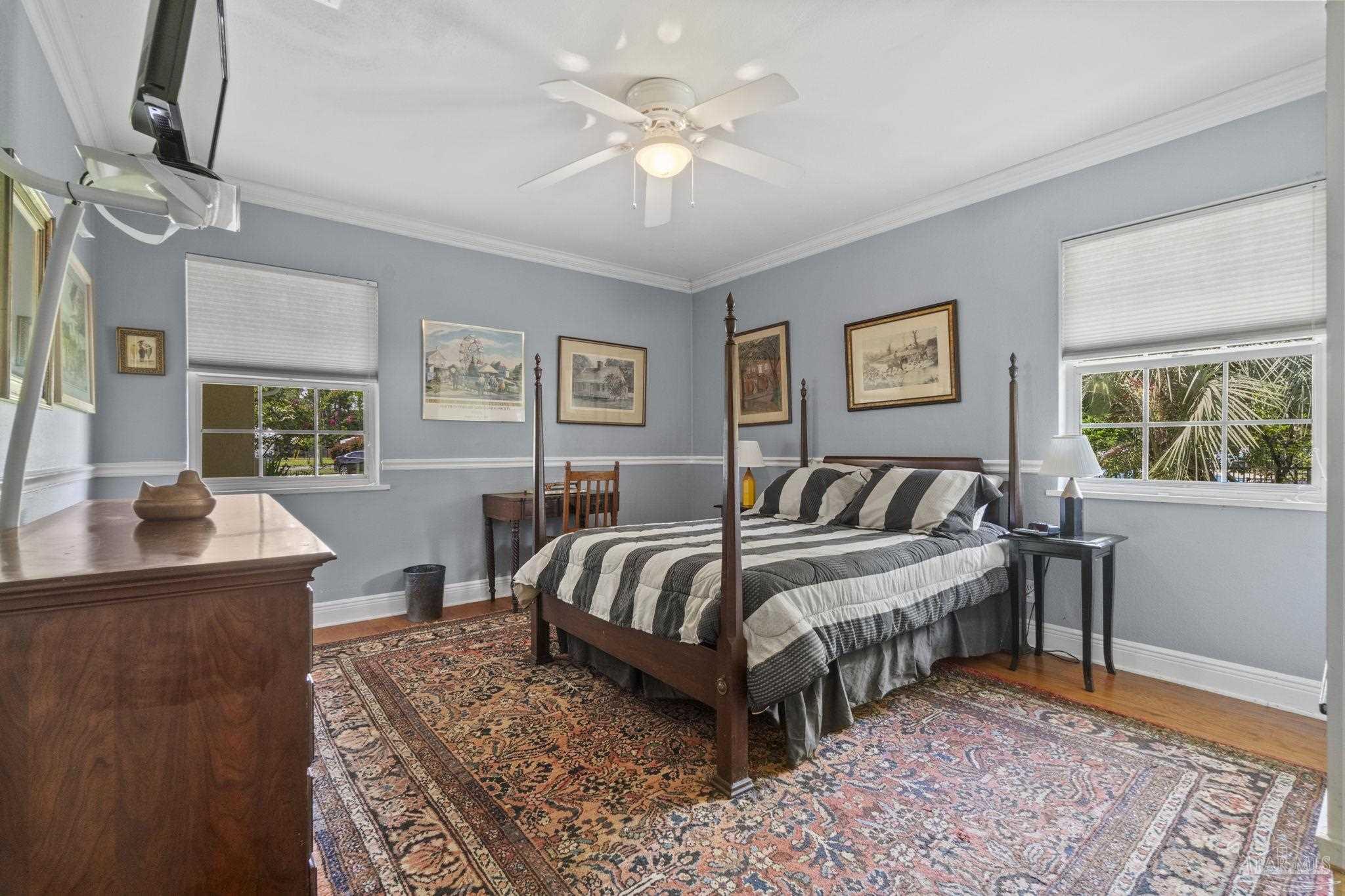 Bedroom with a four-poster bed, striped bedding, and a large patterned rug.