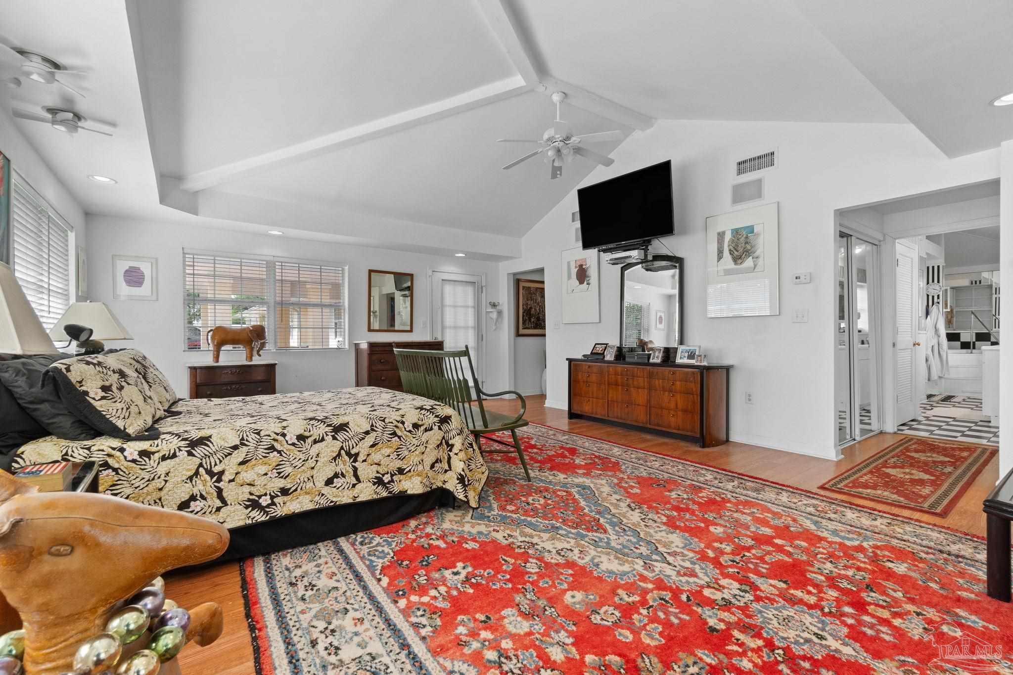 Furnished bedroom with a vaulted ceiling, patterned rugs, and an adjoining bathroom.