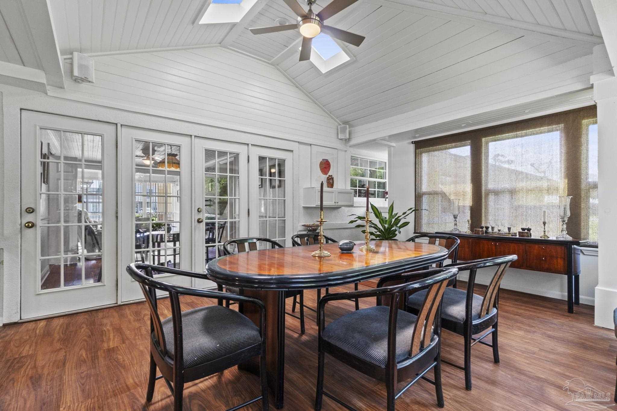Dining room with a polished wood table beneath a vaulted ceiling with skylights.
