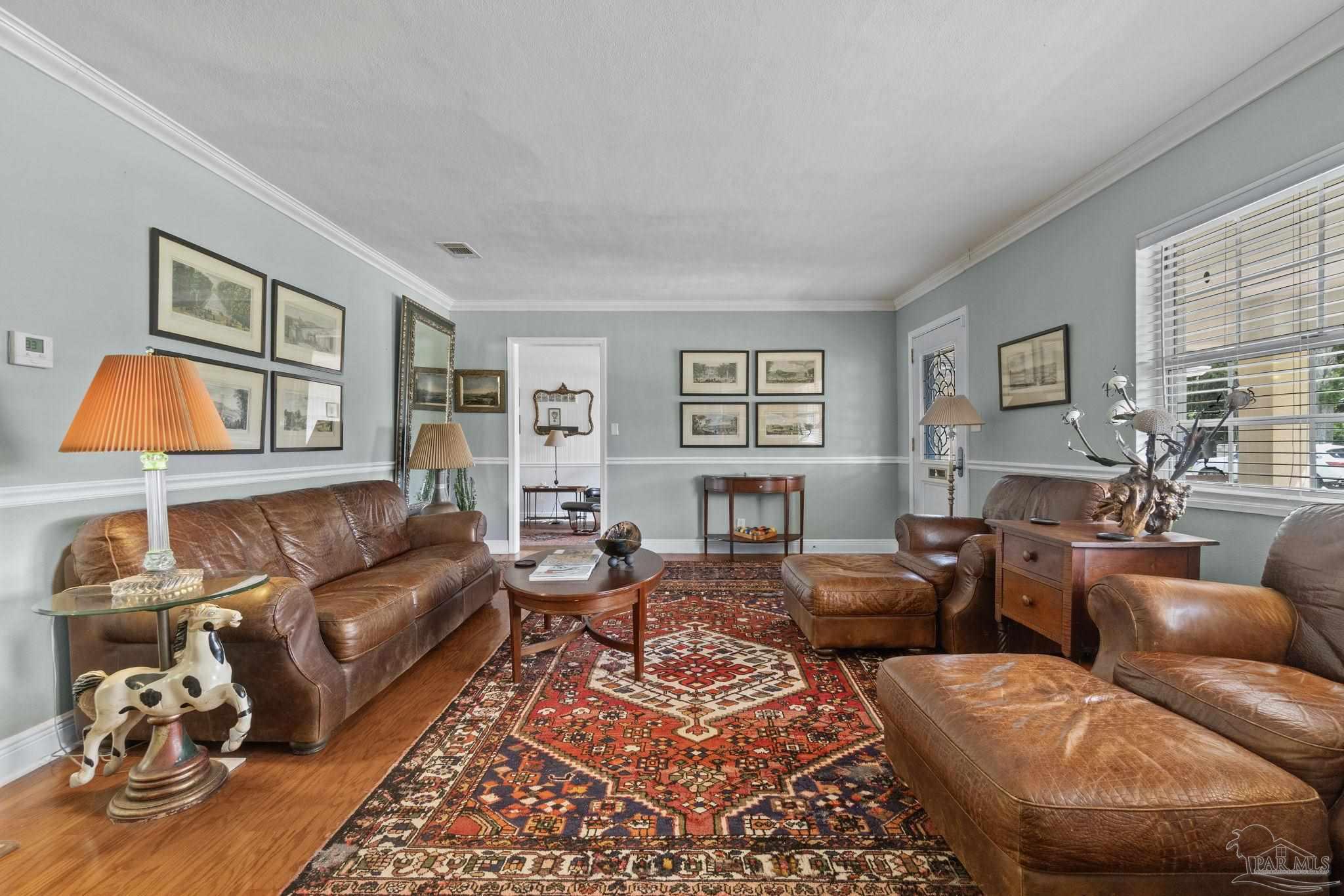 Furnished living room with brown leather seating and a large red patterned rug.