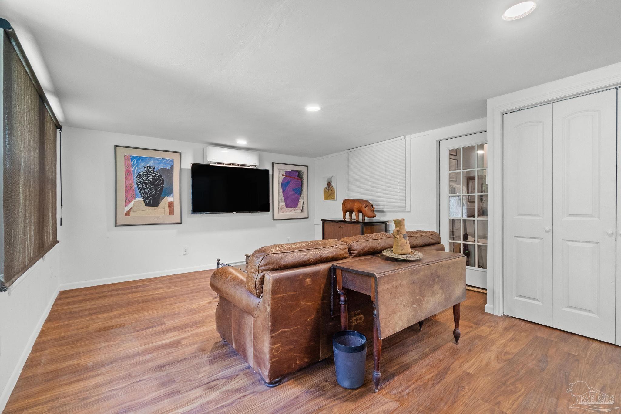 Living room with a brown leather sofa, wooden coffee table, and warm wood flooring.