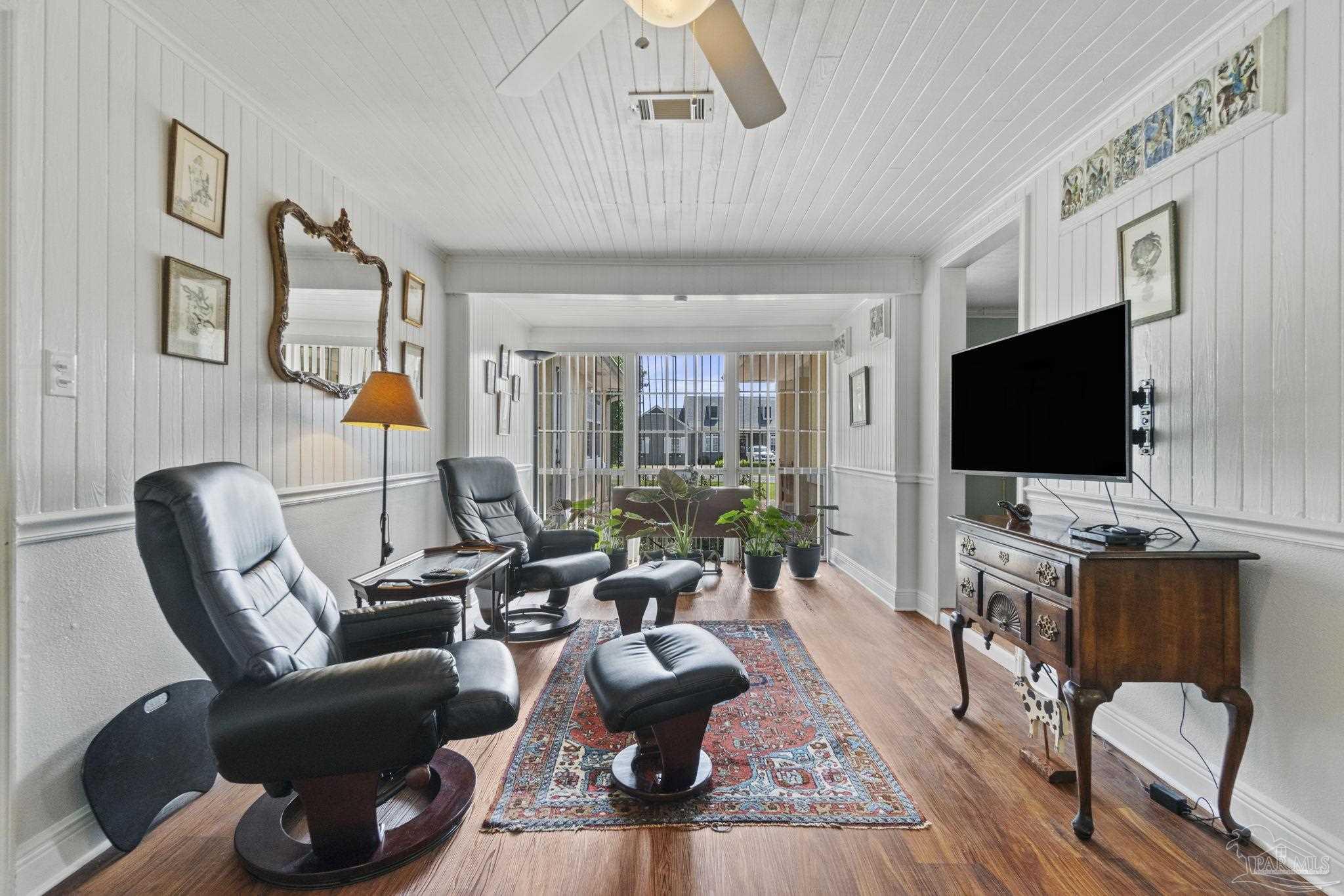 Living room with black leather recliners, a patterned rug, and plants by the rear windows.