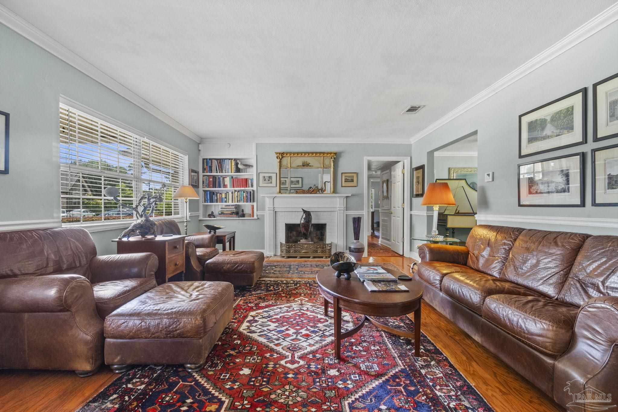 Living room with a white fireplace, built-in bookshelves, leather seating, and a large patterned rug.