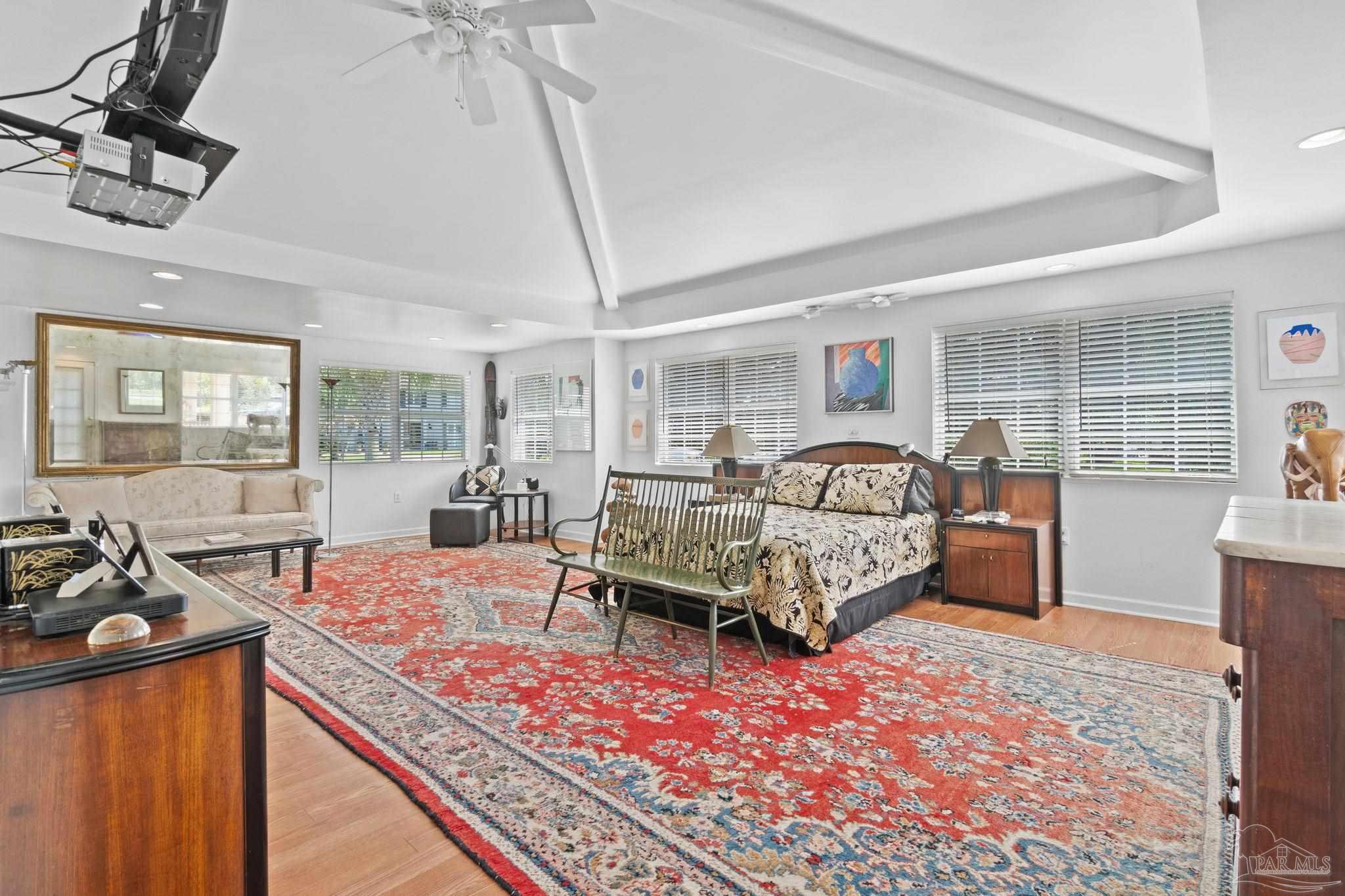 Furnished bedroom with a tray ceiling, large bed, sitting area, and colorful patterned rug.
