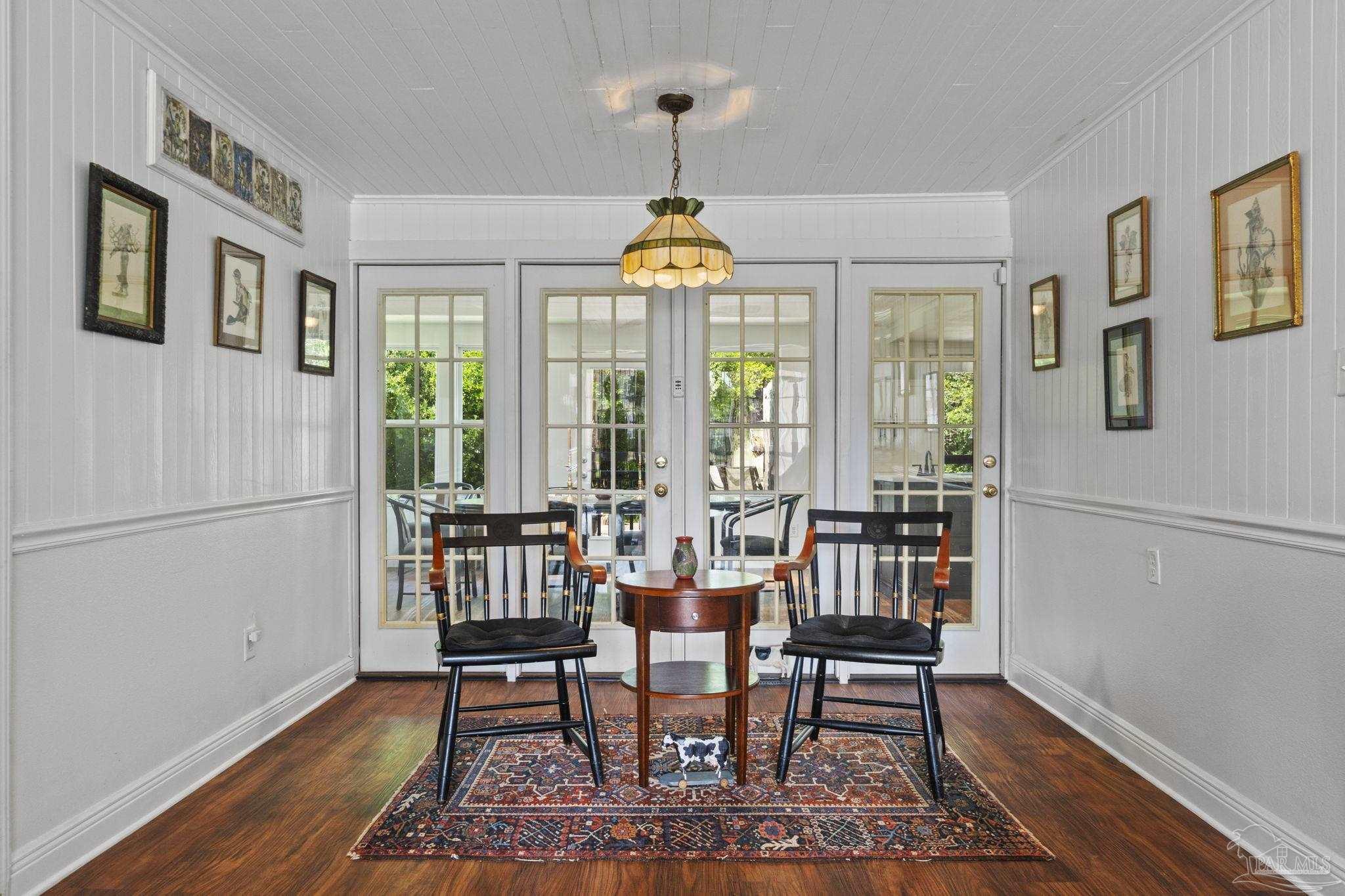 Dining nook with a round table, two chairs, patterned rug, and glass French doors.