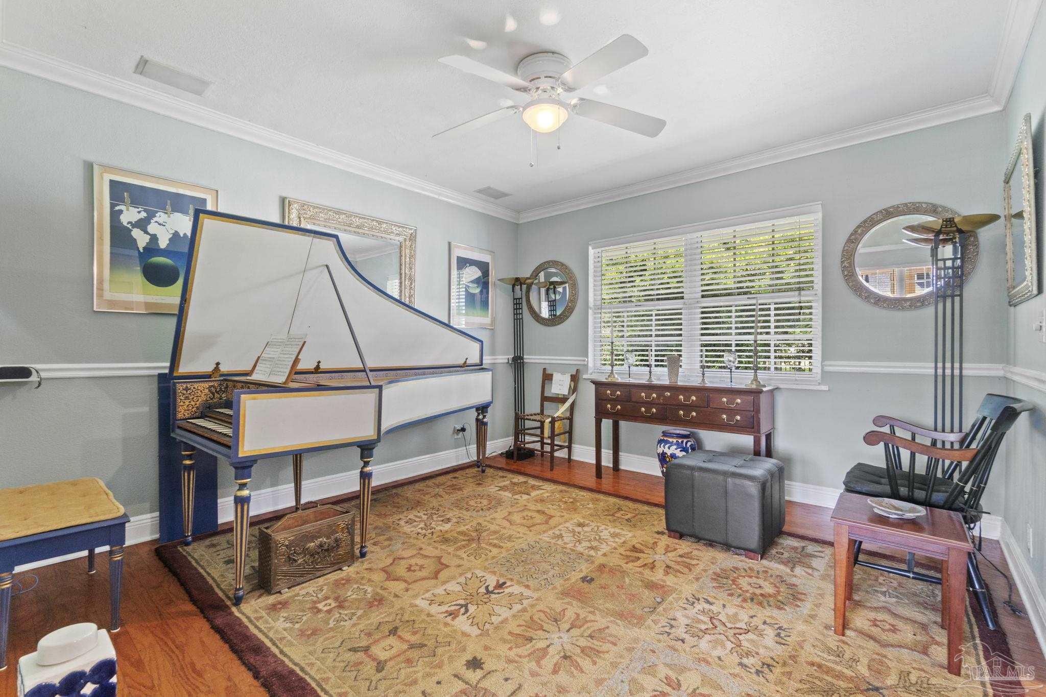 Furnished music room with a blue-and-white harpsichord, patterned rug, and window with white blinds.