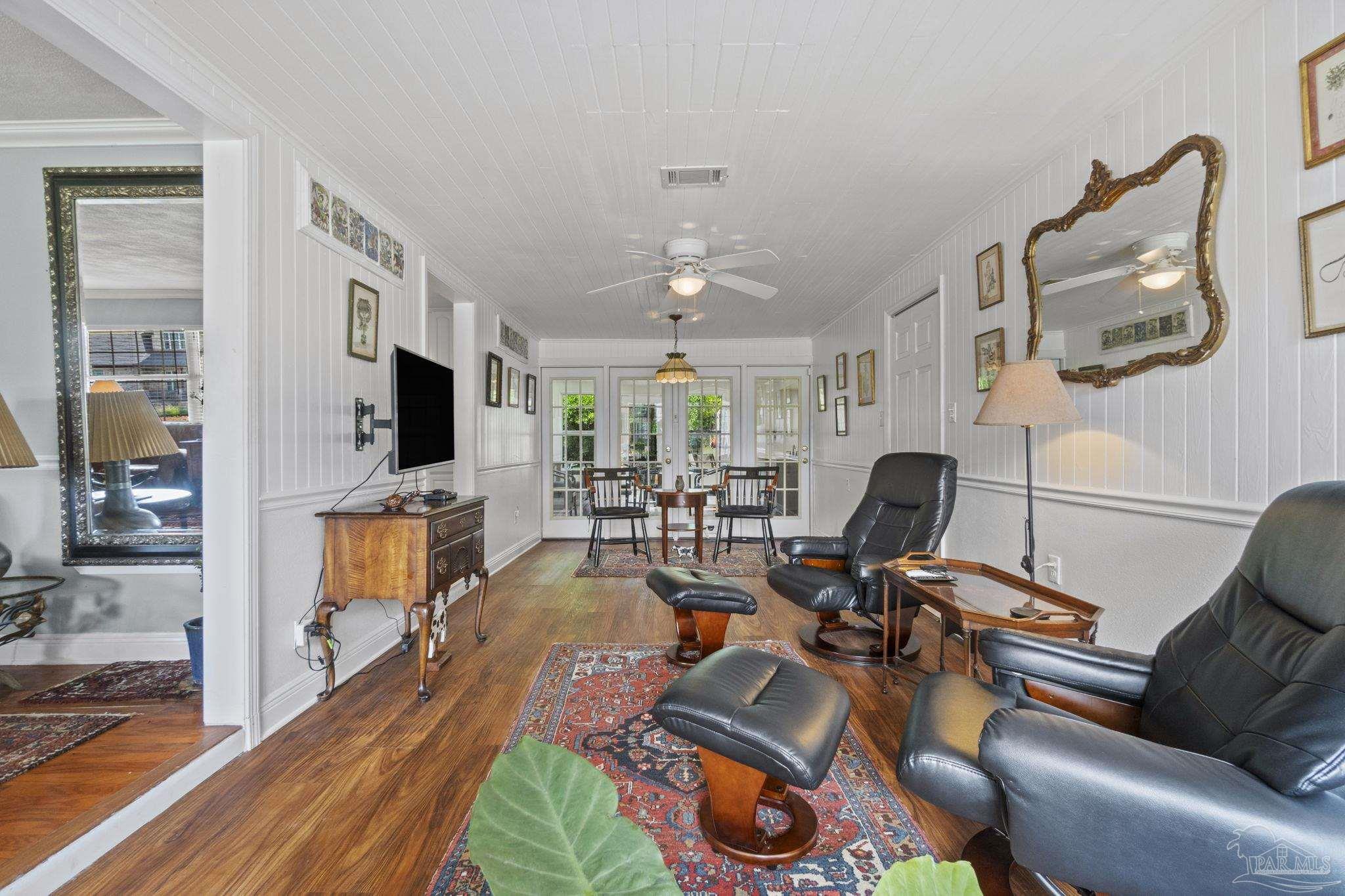 Furnished living room with leather recliners, wood floors, and French doors.