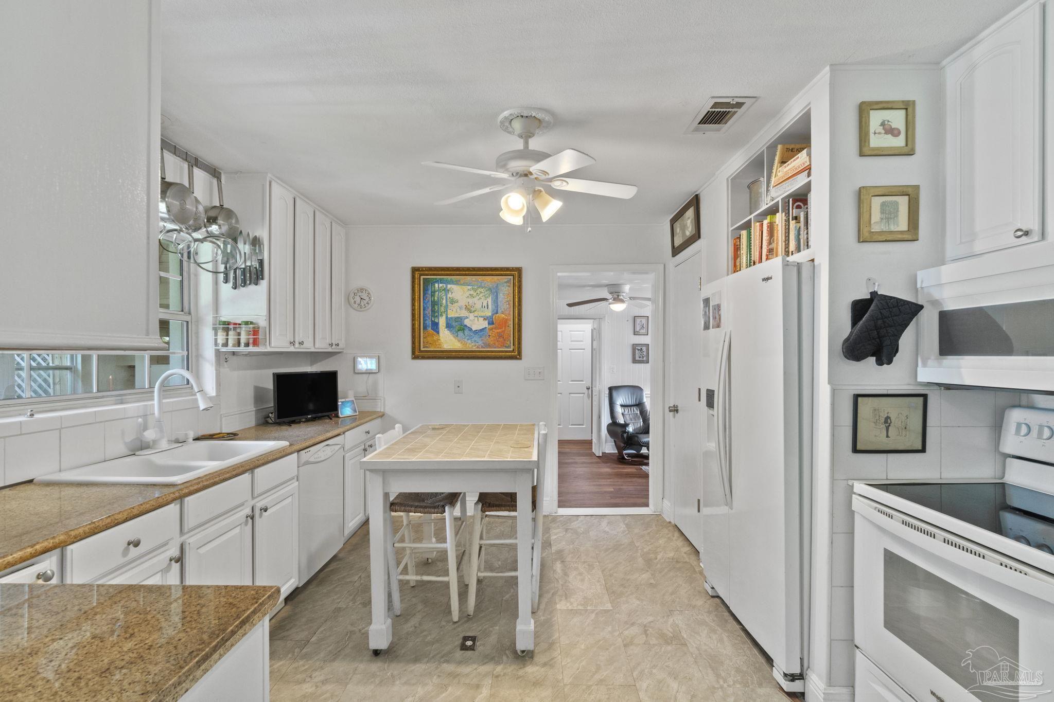 Kitchen with white cabinetry, granite counters, and a tiled island with seating.