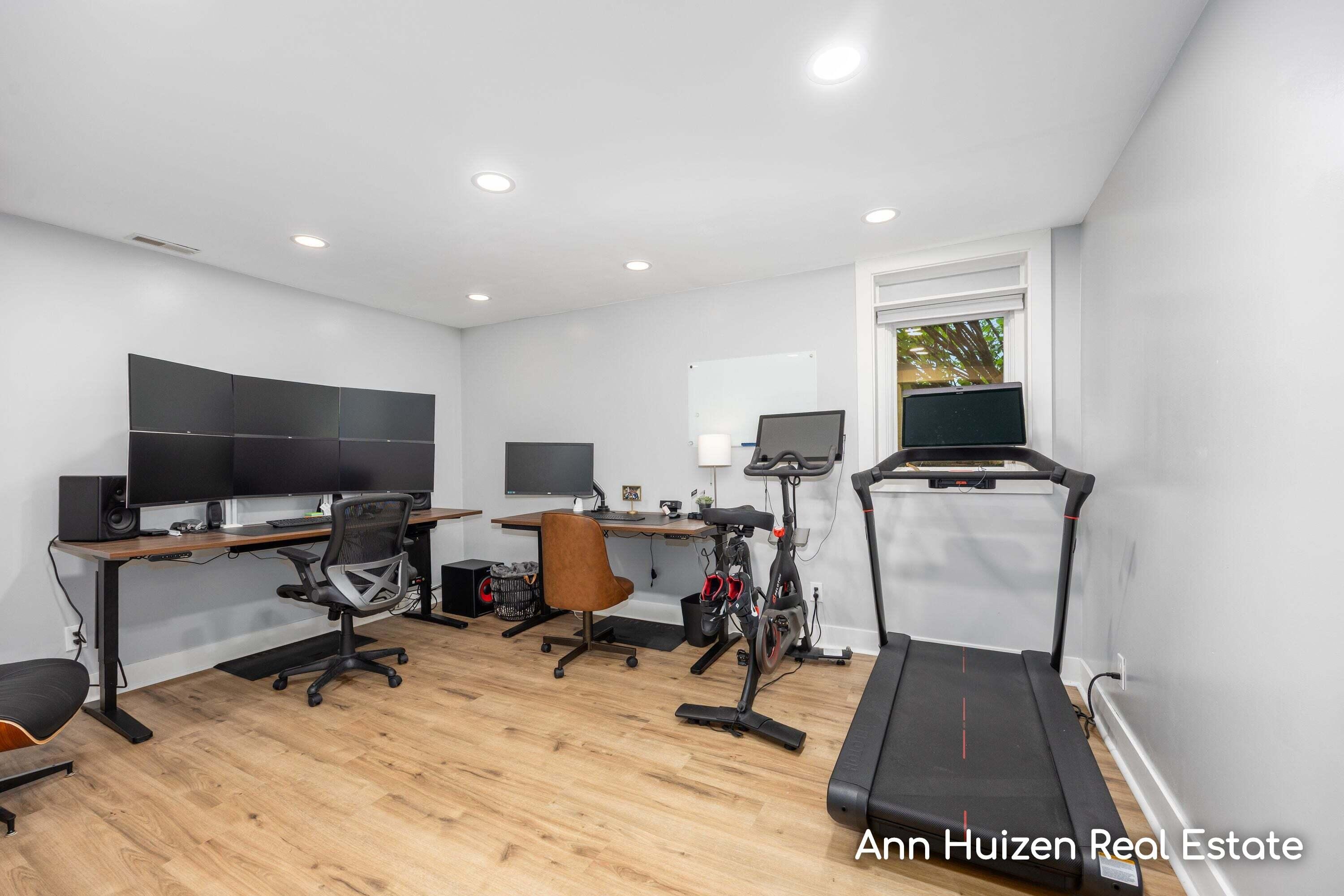 Home office and exercise room with a multi-monitor desk, exercise bike, and treadmill.