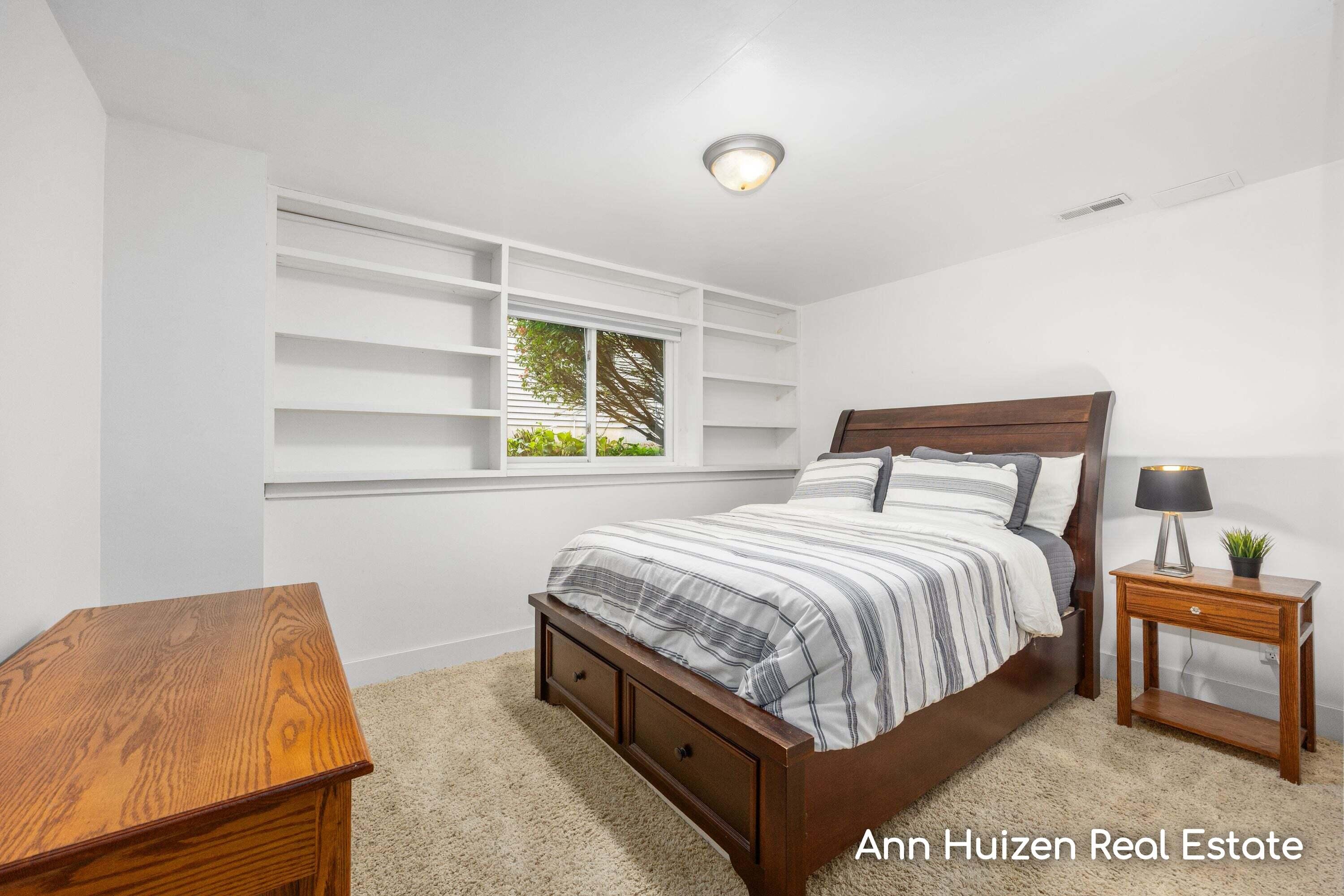 Bedroom with a dark wood storage bed and built-in shelves around the window.