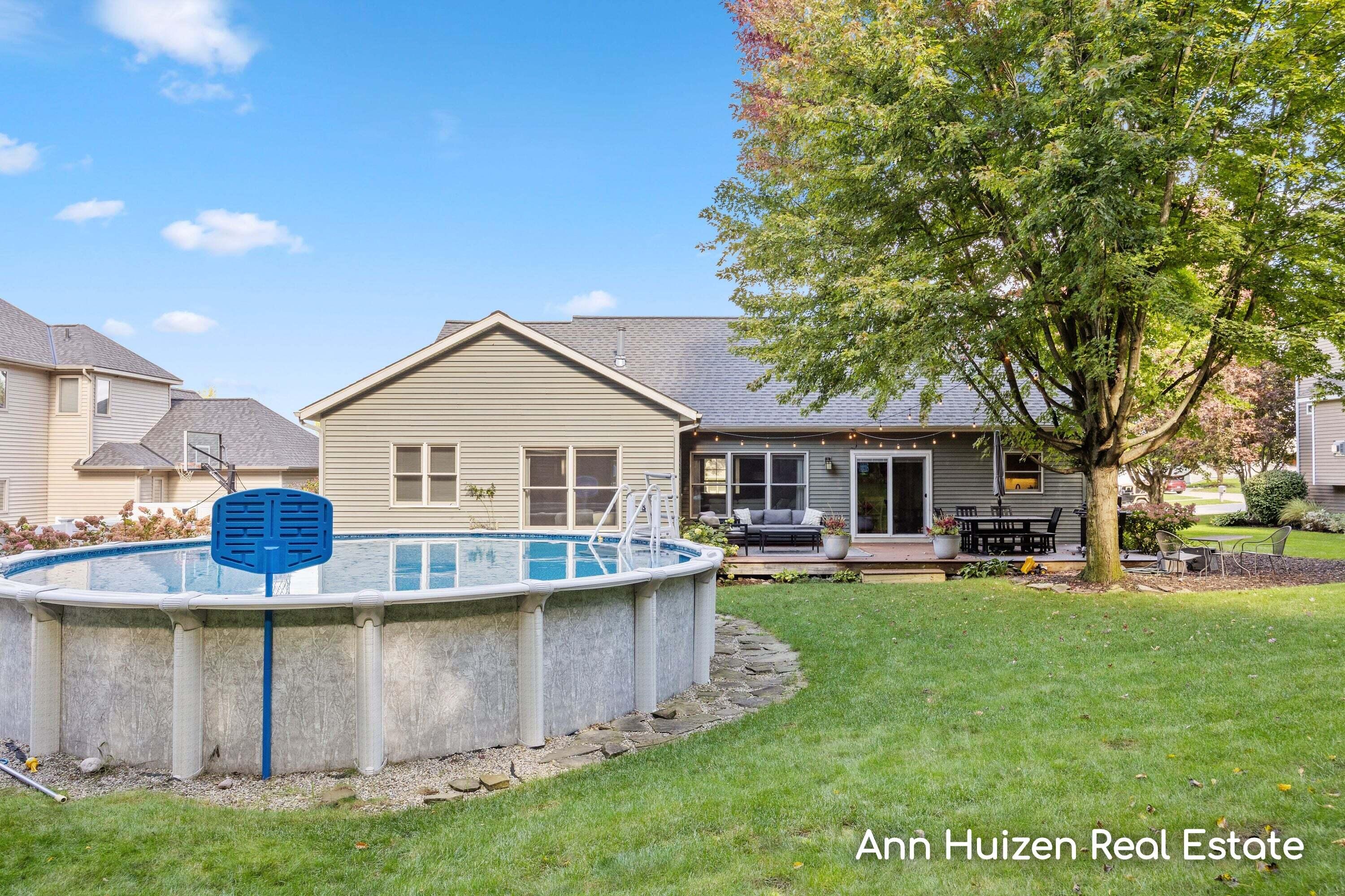 House backyard with an above-ground pool, furnished patio, and large shade tree.