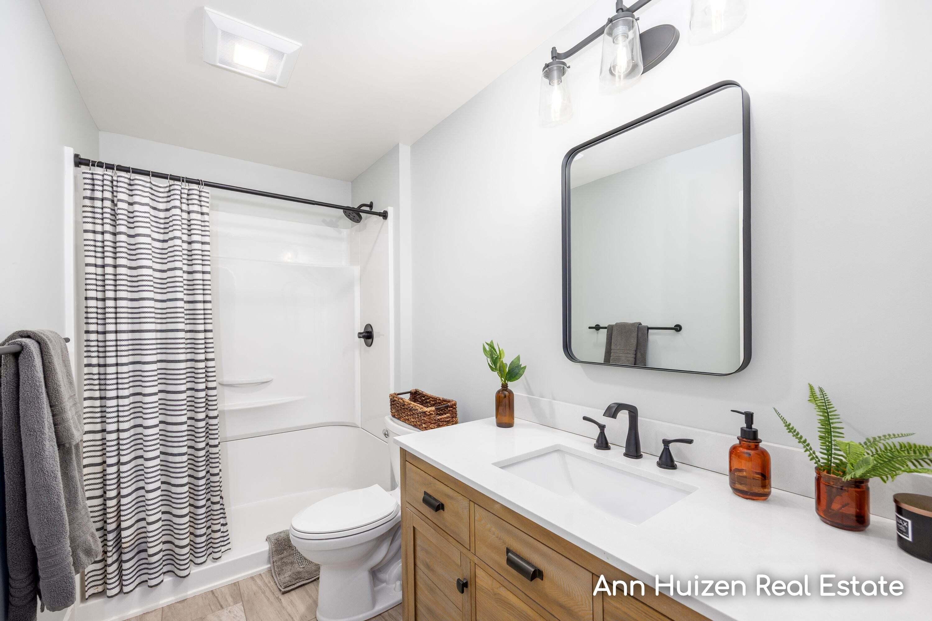 Bathroom with a wood vanity, black-framed mirror, and striped shower curtain.