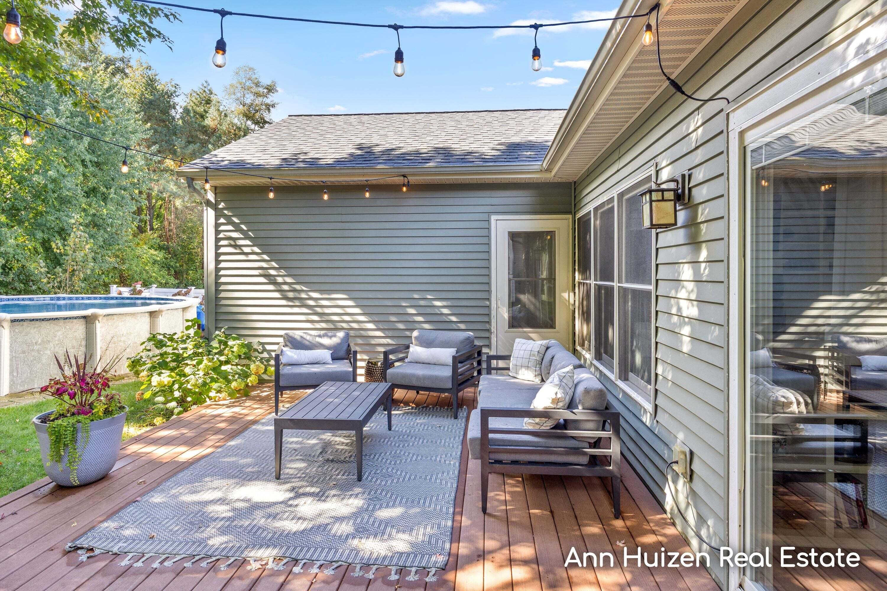 Furnished backyard deck with lounge seating, string lights, and an above-ground pool.