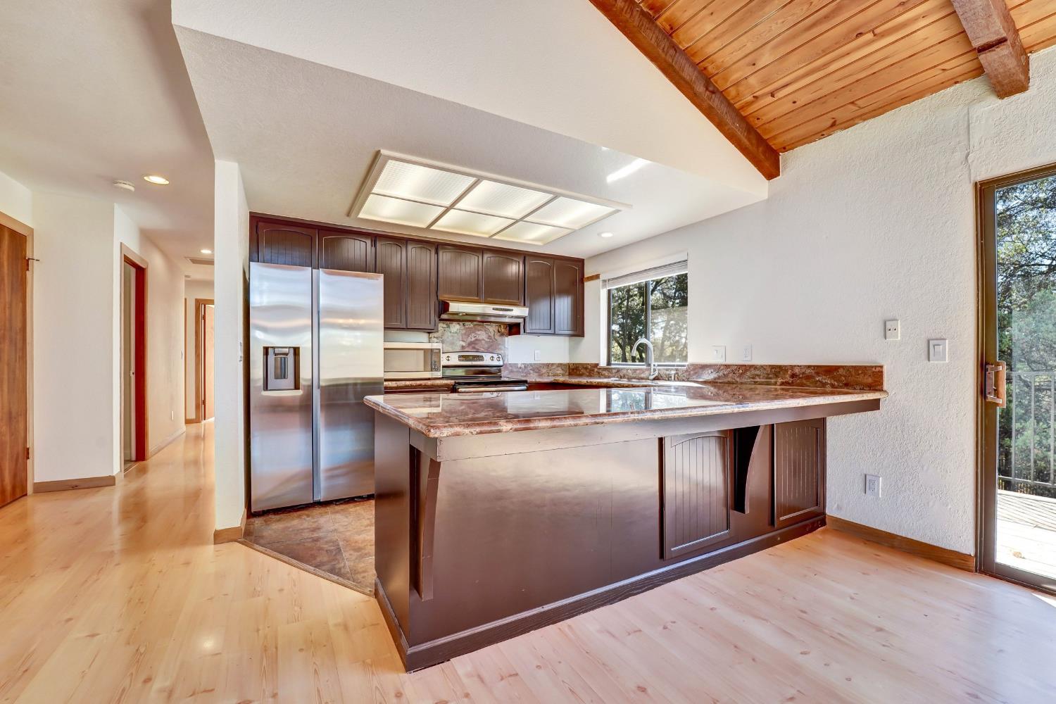 Kitchen with a large island, stainless steel appliances, and a vaulted wood-plank ceiling.