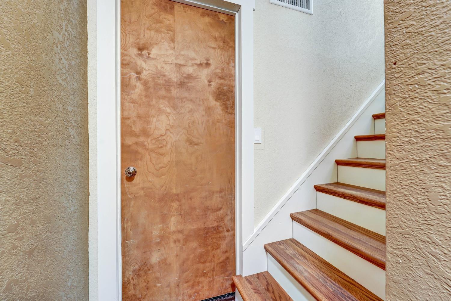 Interior staircase with wood treads and white risers beside a plain wood door.