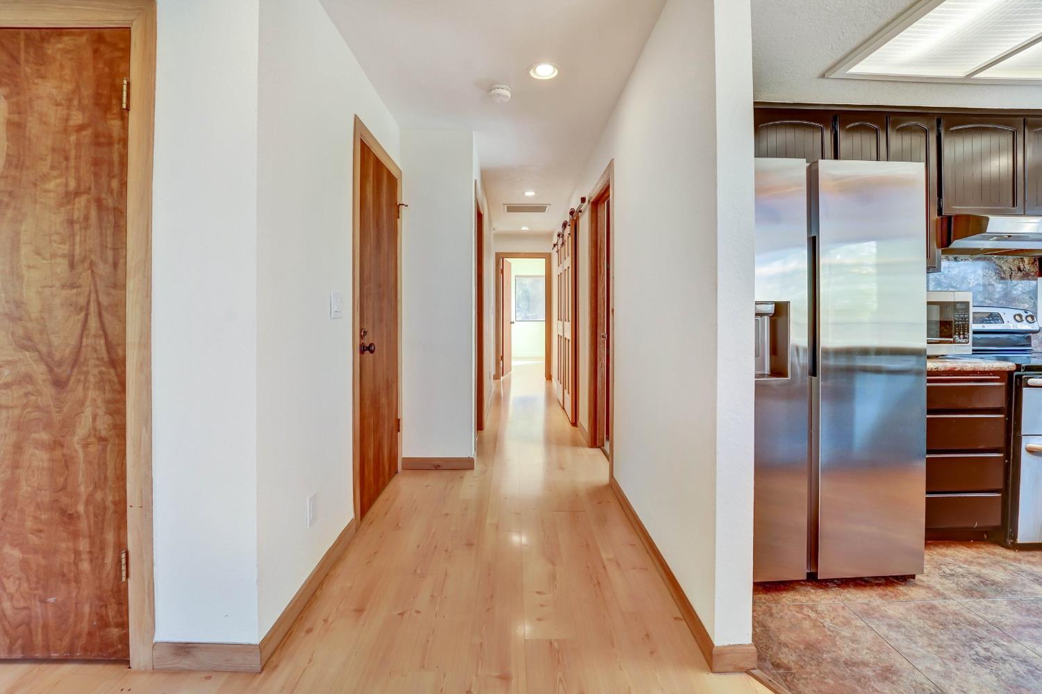Bright hallway with light wood floors and a dark-cabinet kitchen visible to the right.