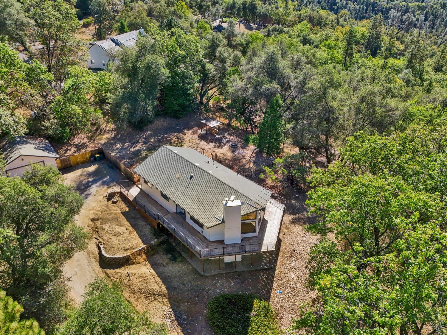 Aerial view of a home with a wraparound deck on a spacious wooded lot.