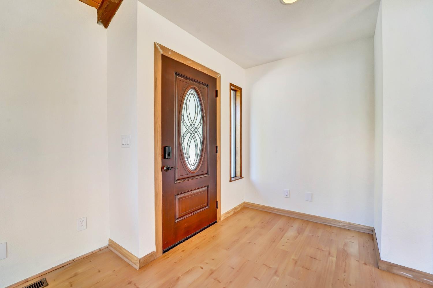 Entry foyer with a dark wood oval-glass front door and light hardwood floors.