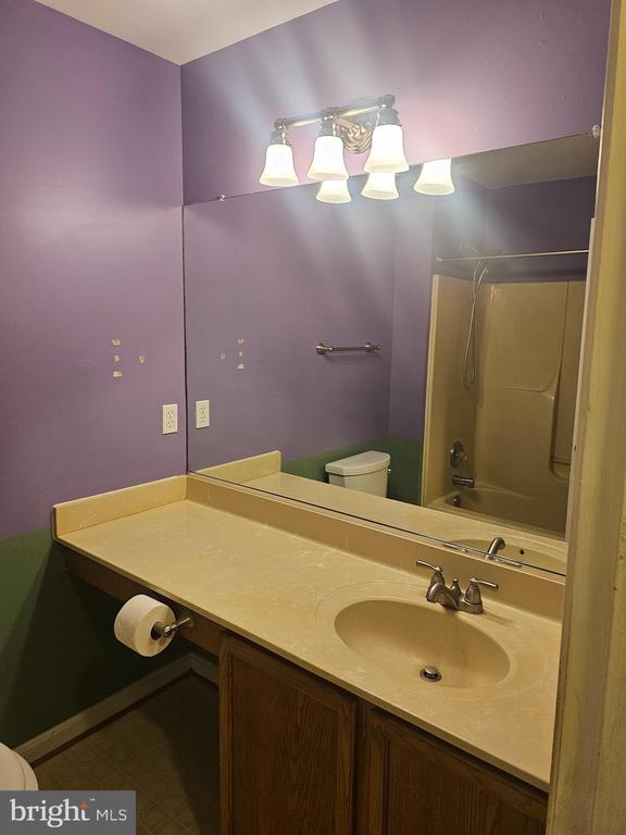 Bathroom with a long beige vanity, large mirror, and purple walls.