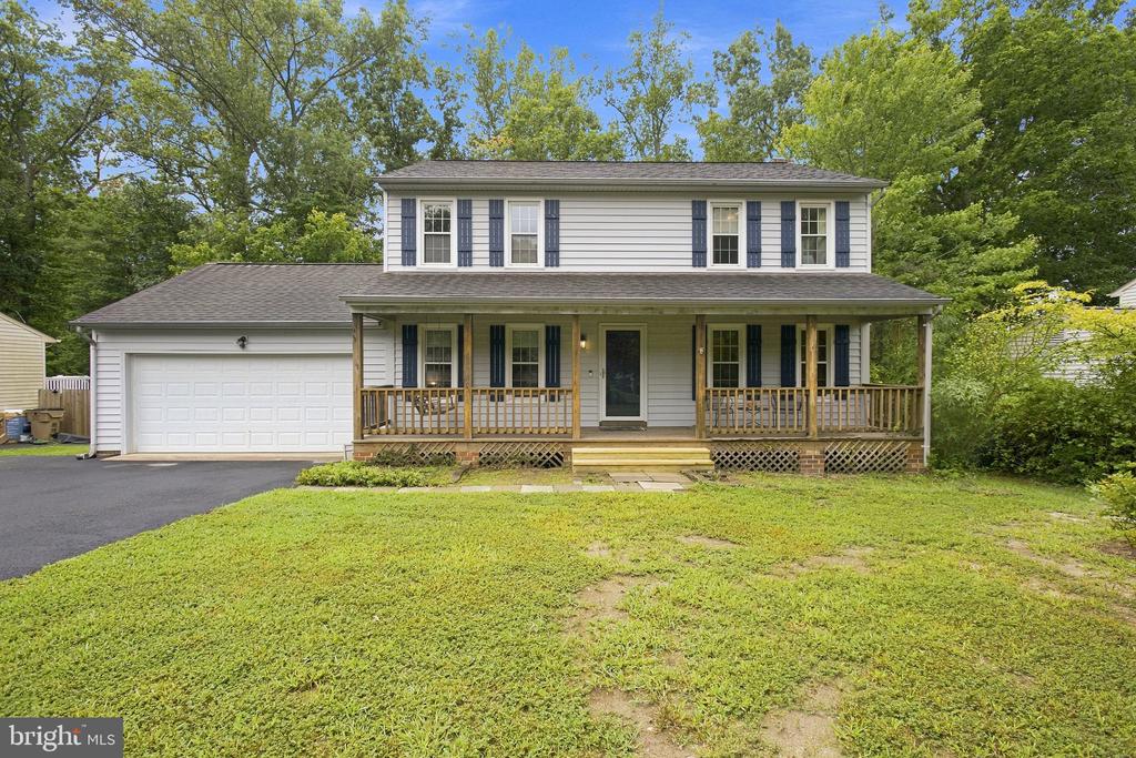 Two-story white house with blue shutters, attached garage, and wide covered porch.