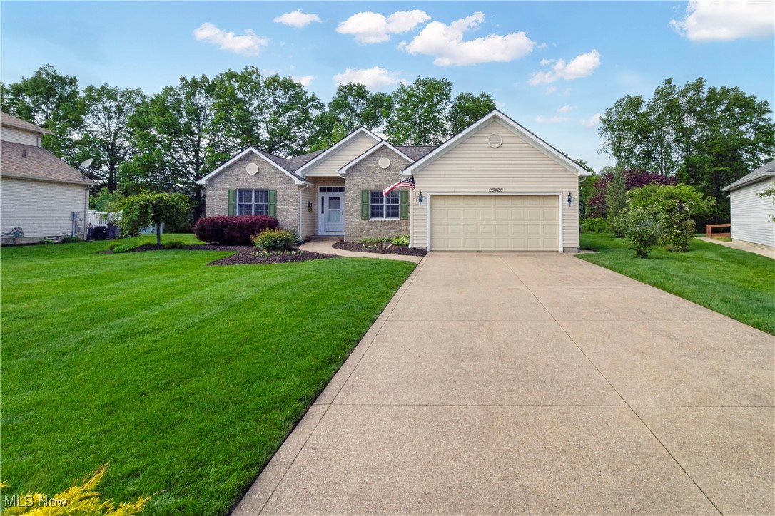 Single-story brick-and-siding house with a two-car garage, broad driveway, and landscaped lawn.