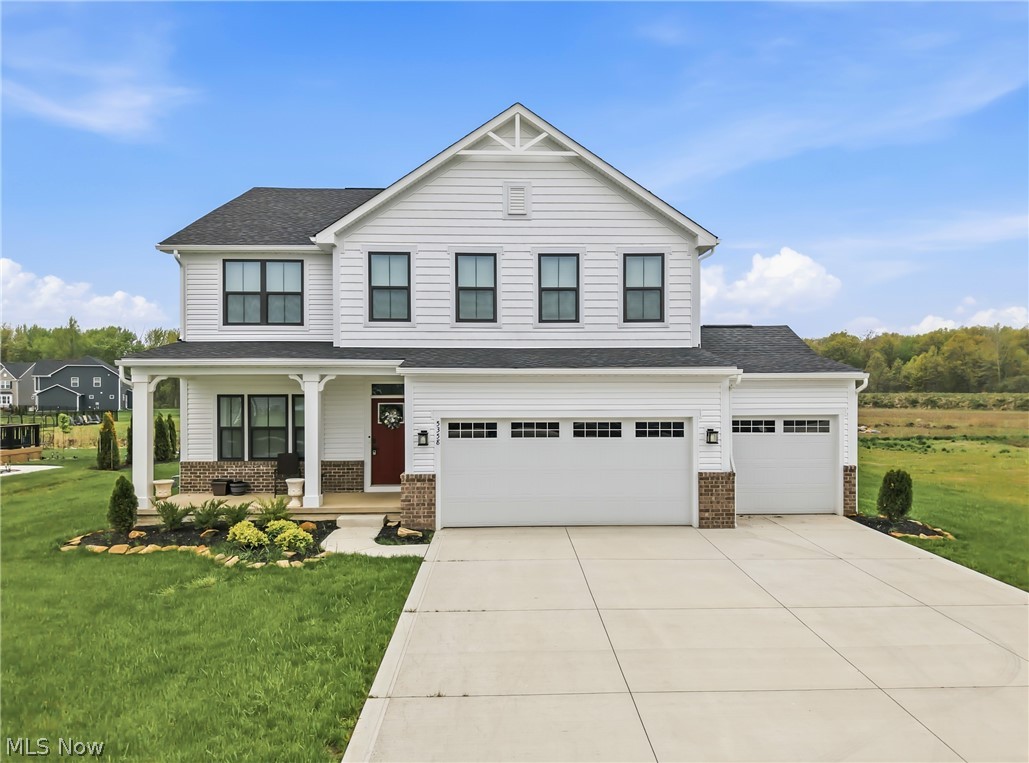 Two-story white house with brick accents, an attached three-car garage, and a wide driveway.