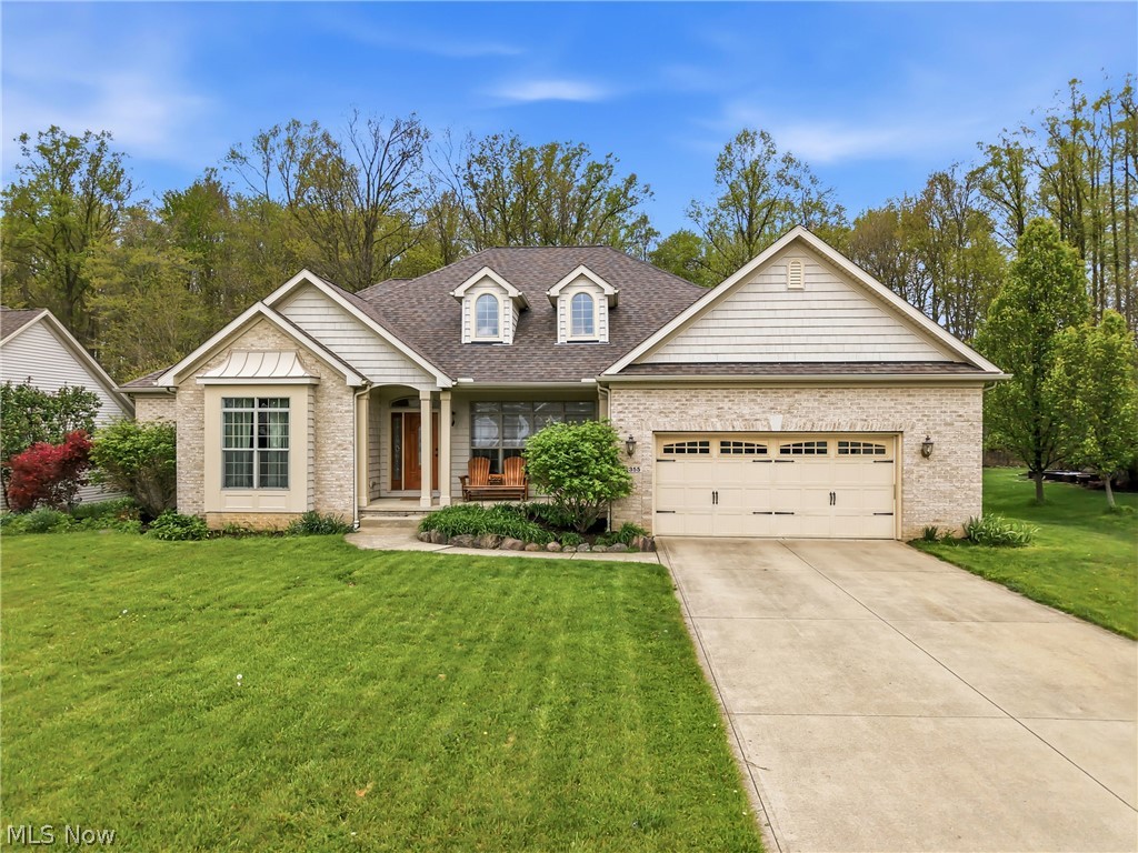 Stone-and-siding home with a two-car garage, broad lawn, and concrete driveway.