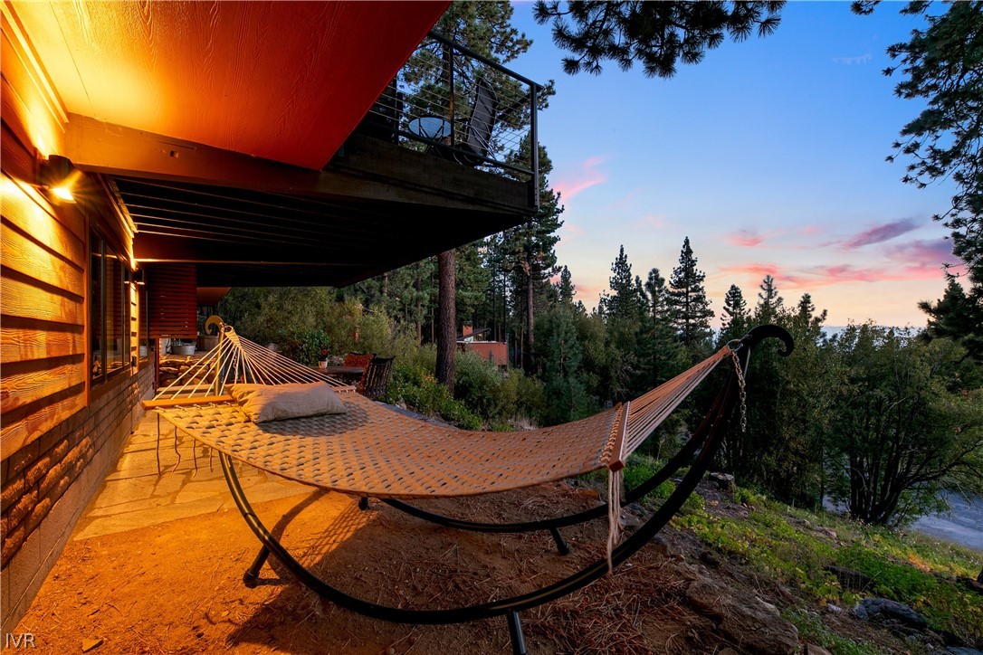 Covered deck with a hammock overlooking pine trees at dusk.