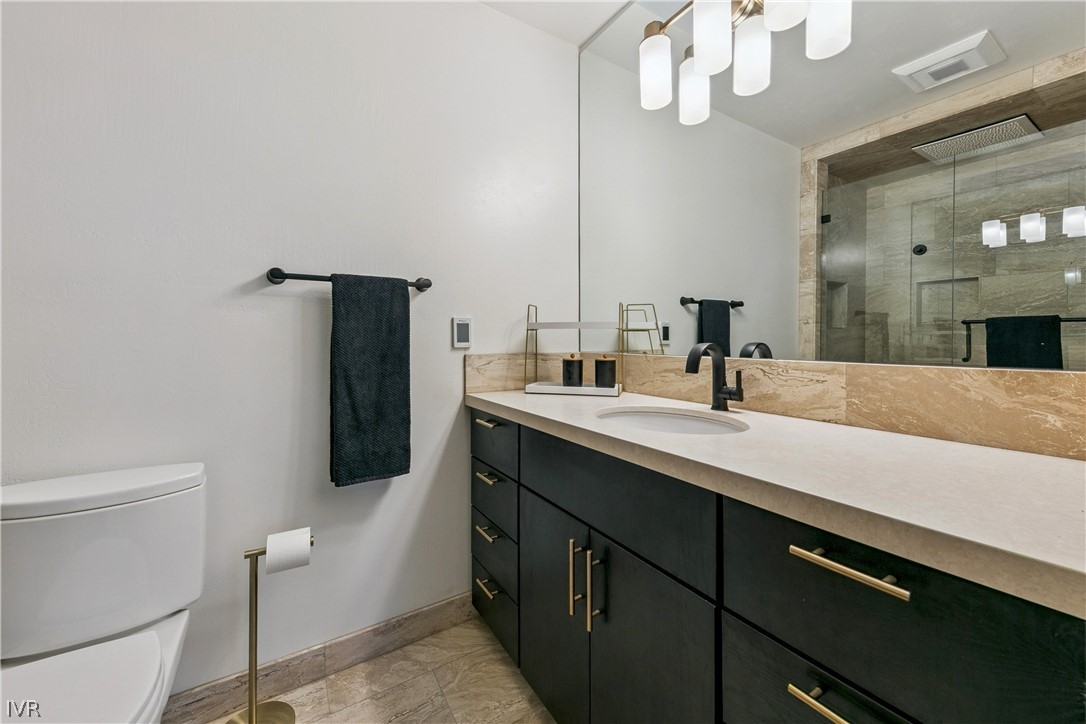 Bathroom with a black vanity, brass hardware, and a large mirror beside a glass-enclosed shower.