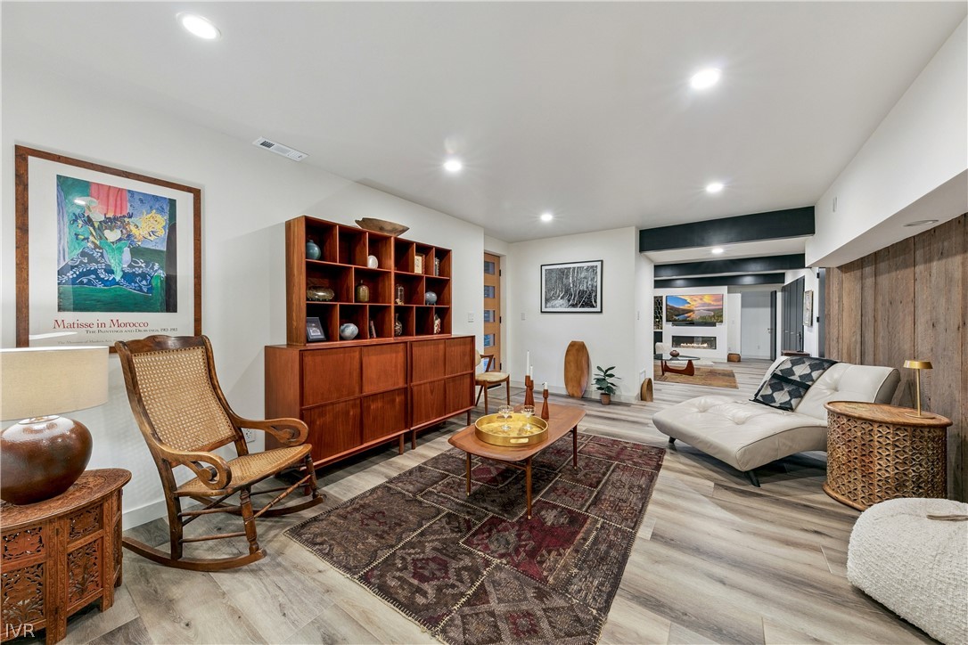 Furnished living room with built-in wood shelving, patterned rugs, and a white sectional.