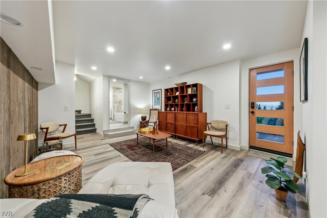 Living room with a modern wood-and-glass entry door, built-in shelving, and stairs.