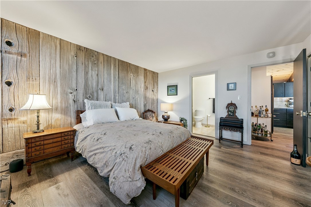 Furnished bedroom with a weathered-wood accent wall, large bed, and wooden bench.