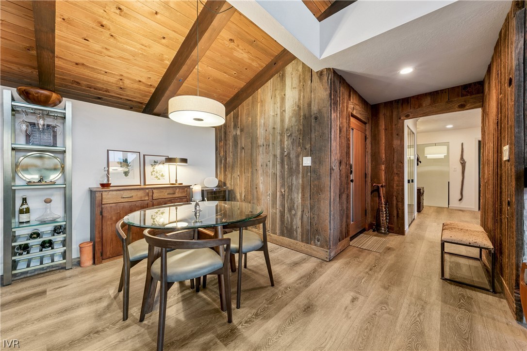 Dining area with a glass-top table beneath a vaulted wood ceiling and beside reclaimed wood walls.
