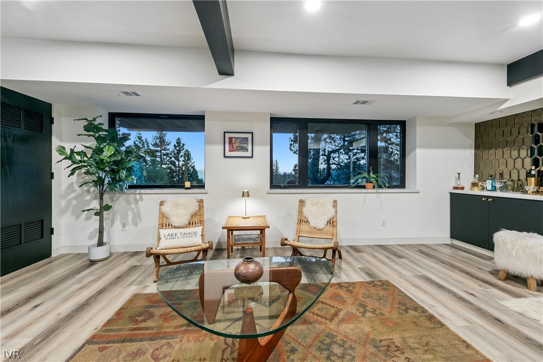 Living room with cane chairs, a glass coffee table, and wide windows overlooking trees.