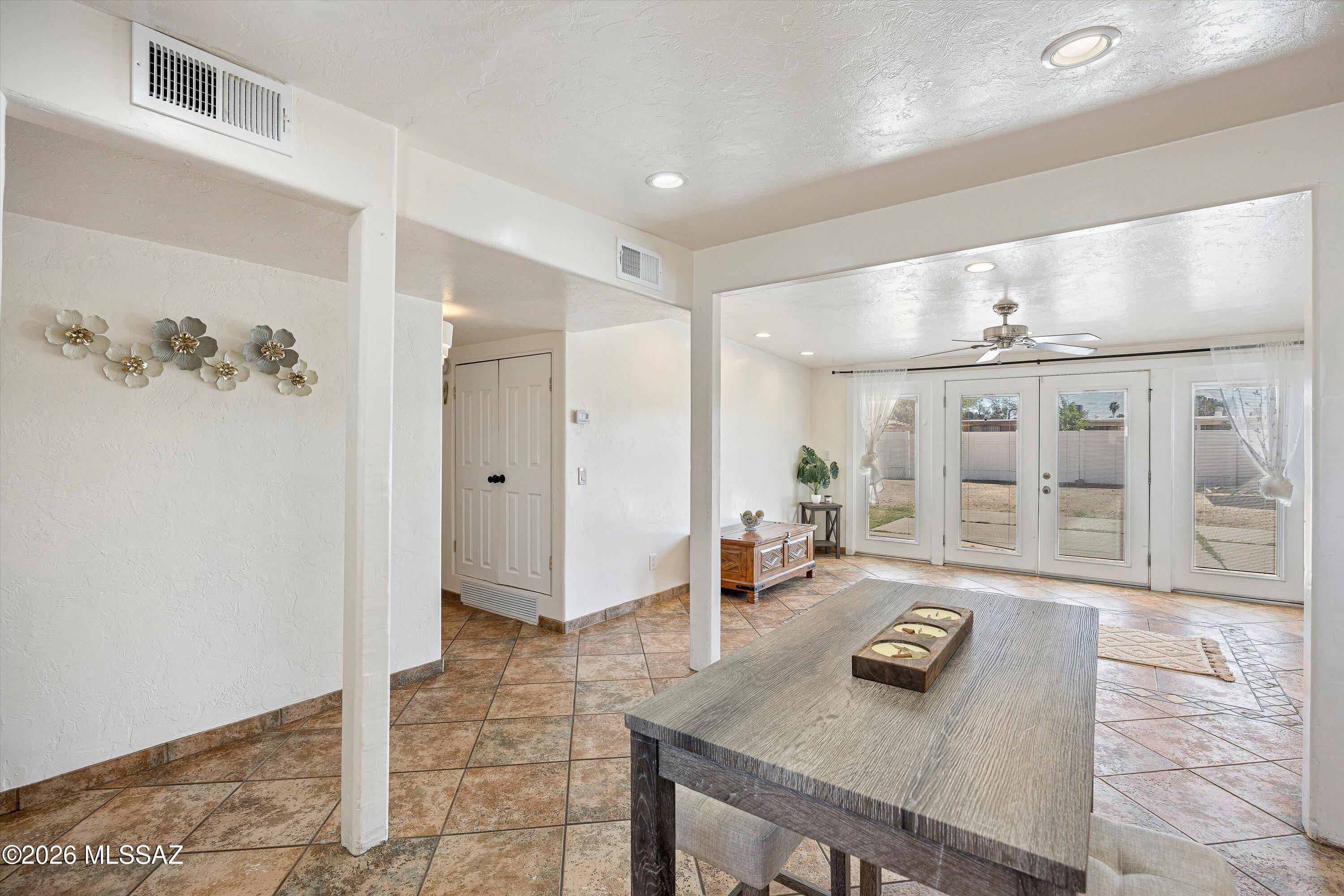 Dining area with tiled floors, a dark table, and French doors opening to the backyard.