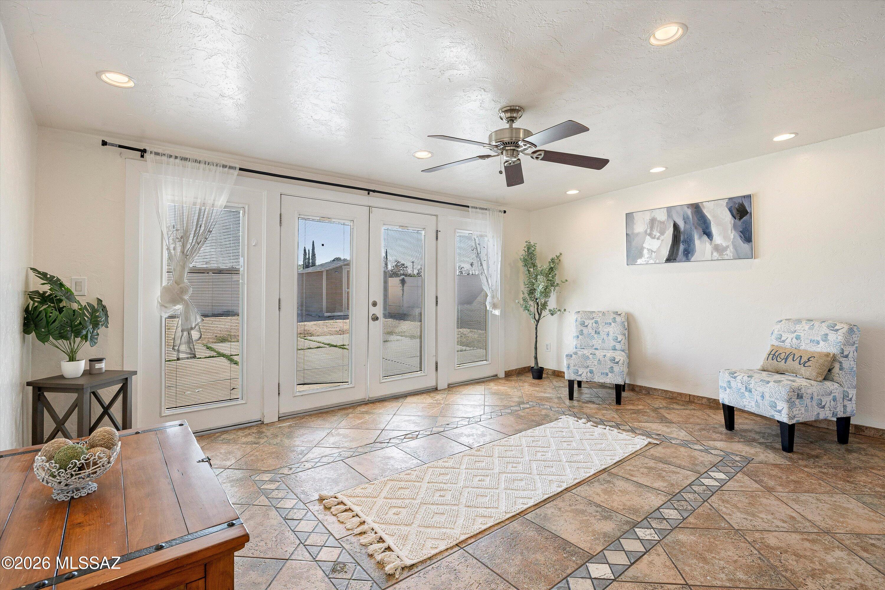 Staged sitting room with patterned tile floors, glass-paneled doors, and two upholstered chairs.