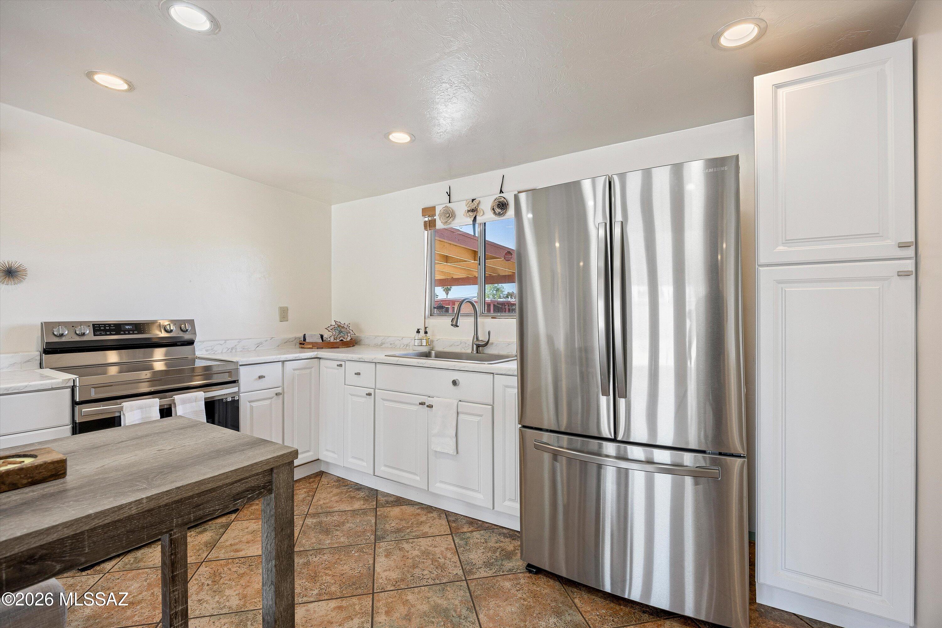 Kitchen with white cabinets, stainless steel appliances, and a sink beneath a window.