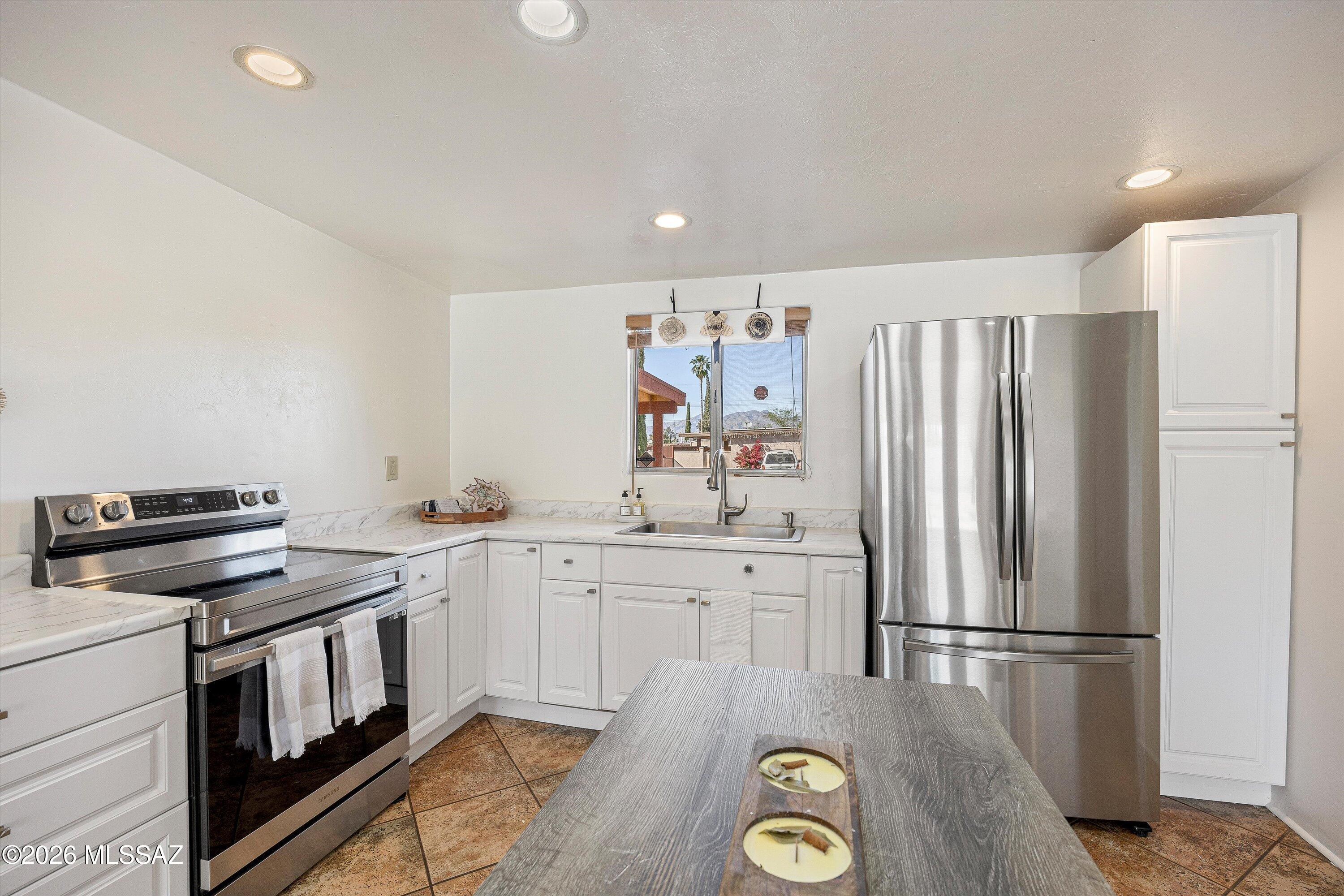 Bright white kitchen with stainless steel appliances and a window overlooking mountains.