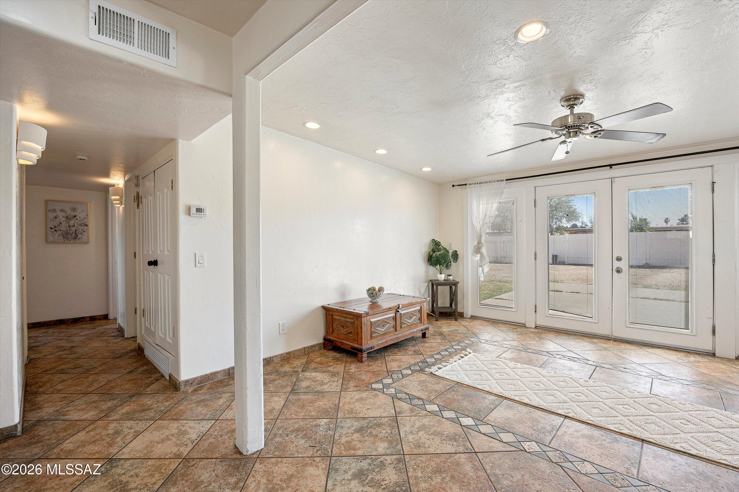 Living room with patterned tile flooring, a wooden chest, and glazed doors to the backyard.