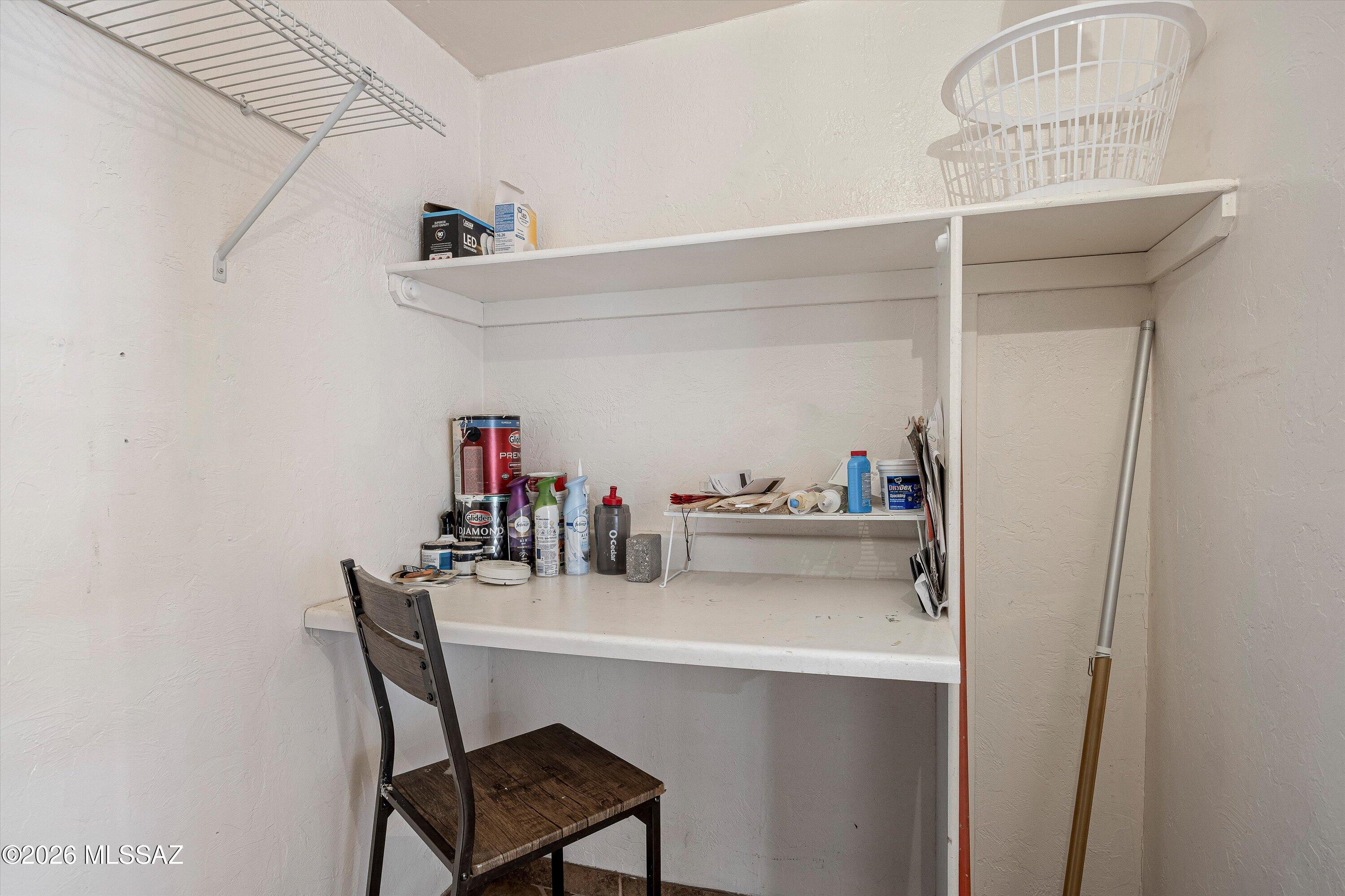 Utility workspace with built-in counter, shelves, paint supplies, and a chair.
