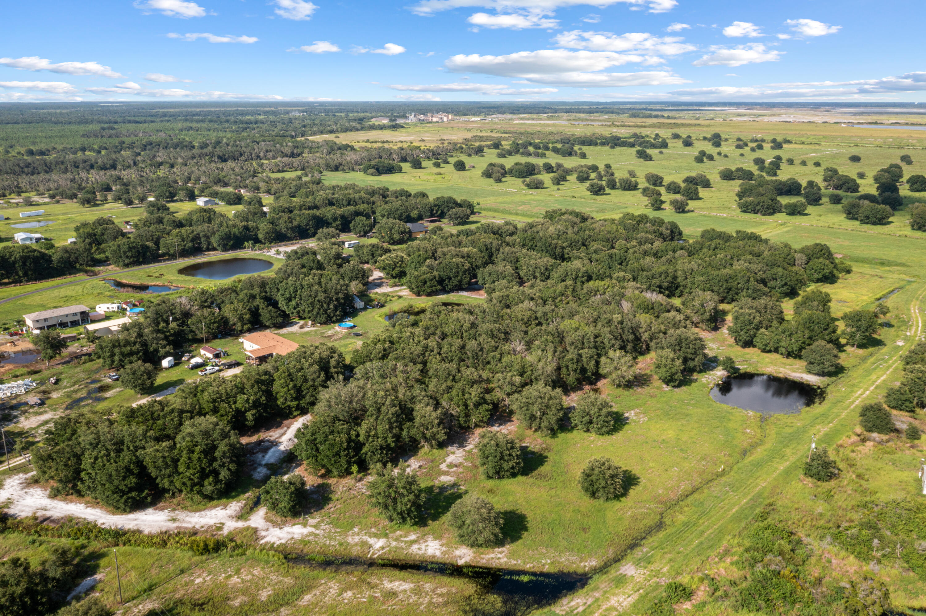Aerial view of wooded acreage with open fields and two ponds.