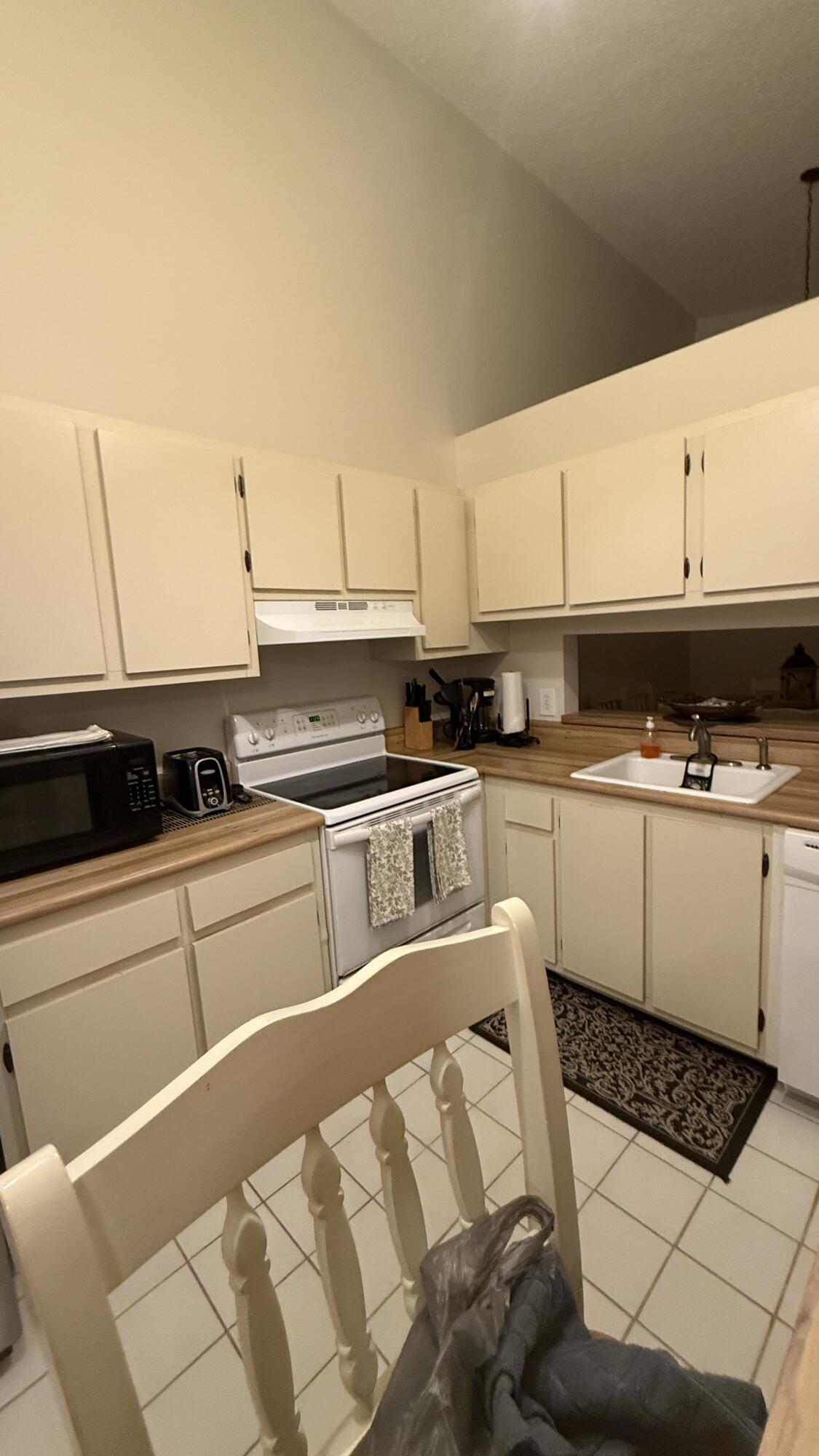 Kitchen with cream cabinets, wood-look counters, a white electric range, and a double-basin sink.
