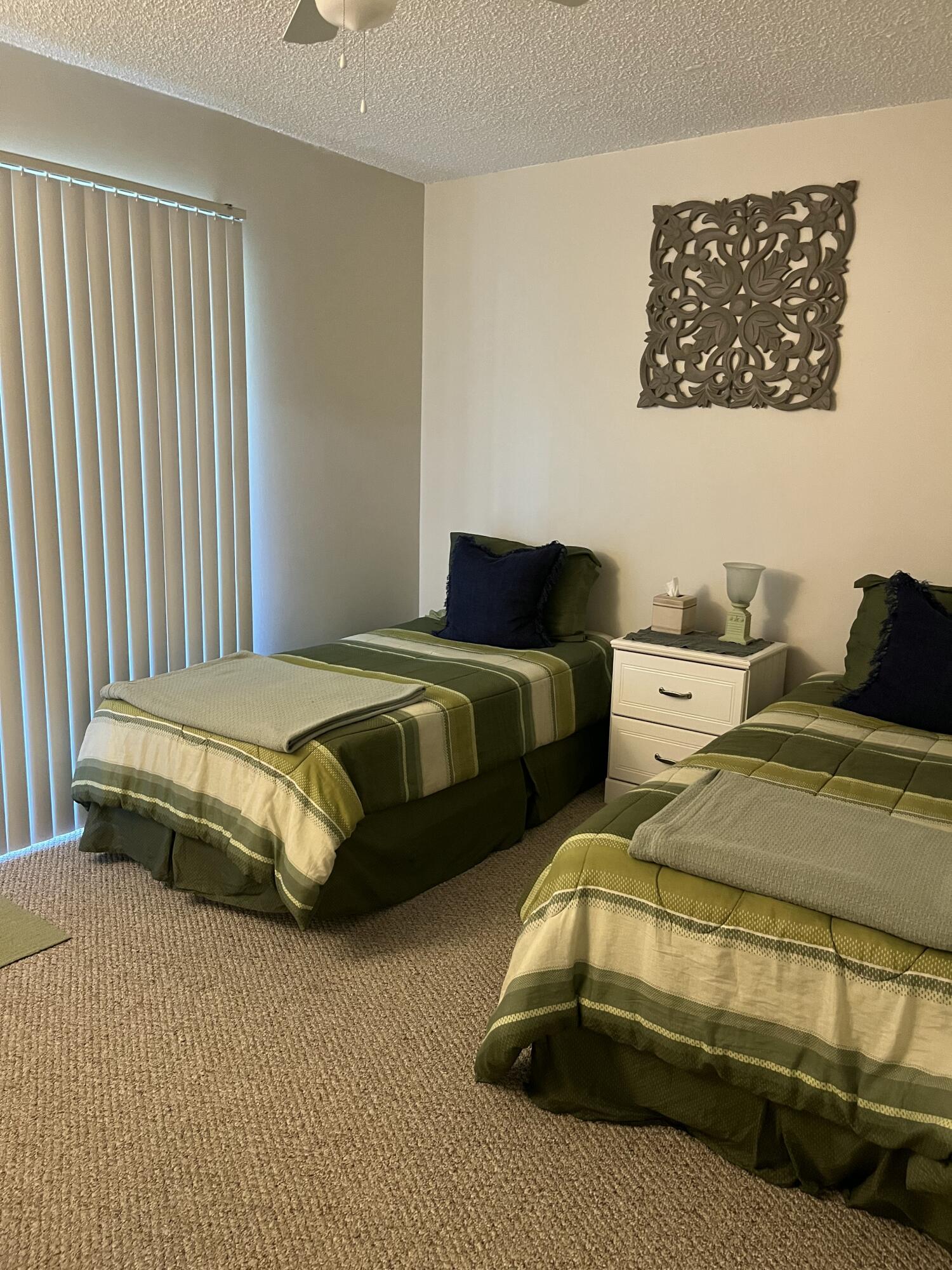 Bedroom with two twin beds in green striped bedding and a nightstand between them.