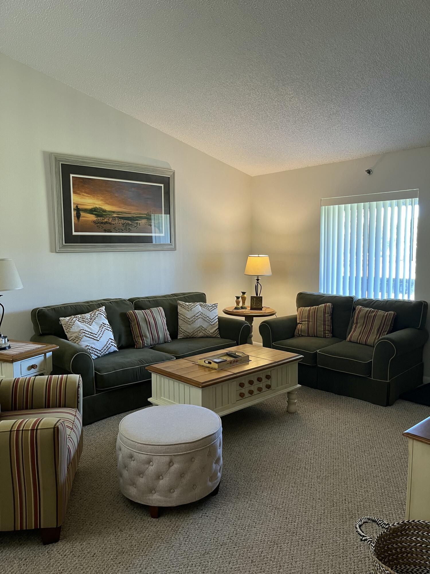 Living room with dark green sofas, a cream coffee table, and a striped accent chair.