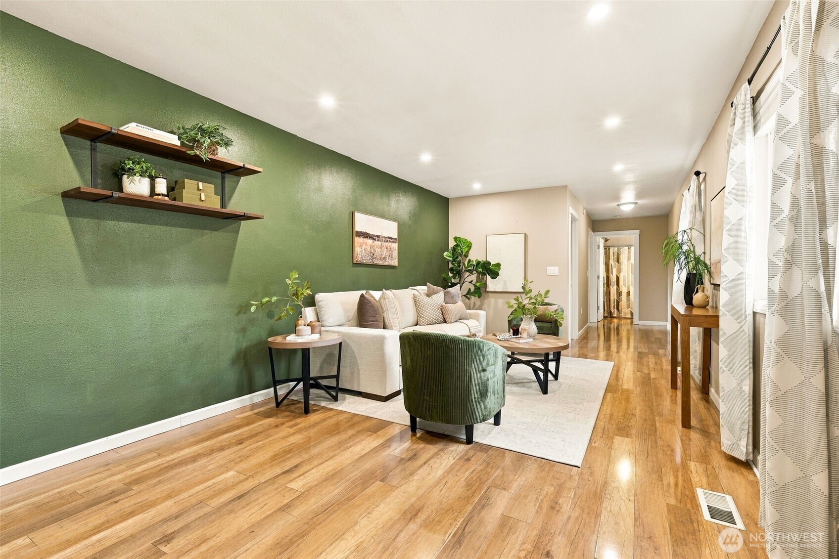 Living room with a deep green accent wall, wood floors, and a cream sofa.