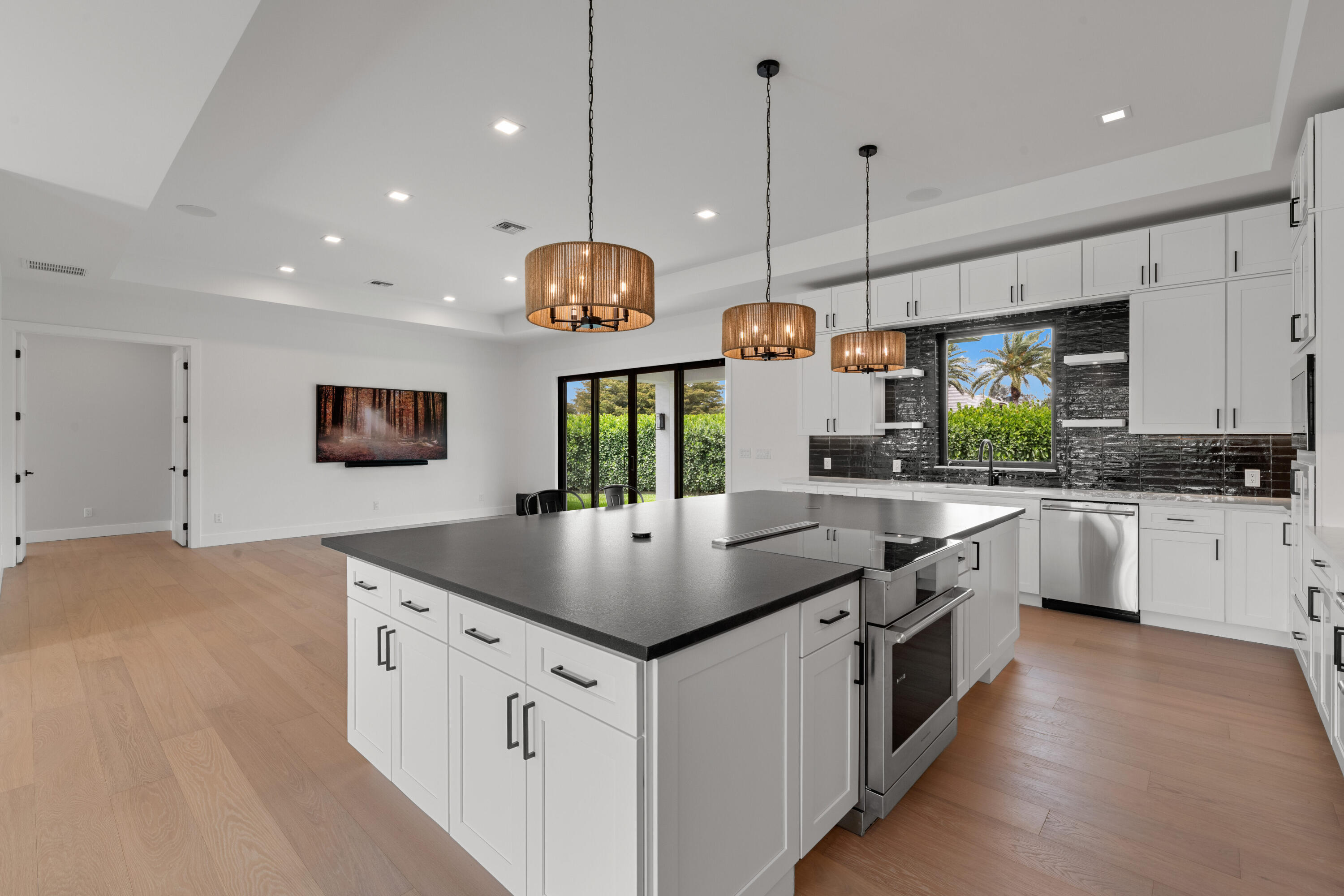 Modern kitchen with a large dark-topped island, white cabinets, and glossy black backsplash.