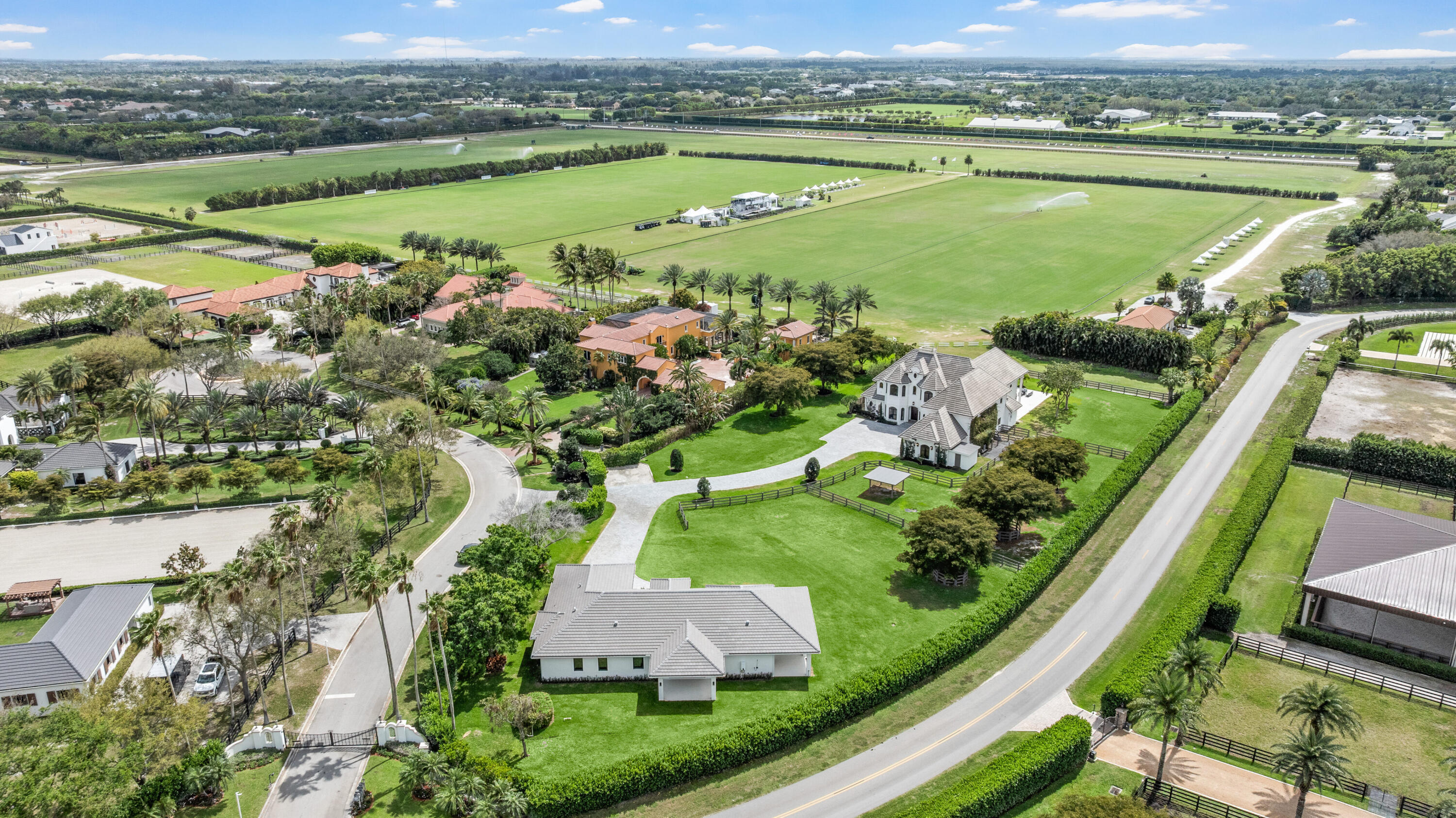 Aerial view of a Wellington estate beside expansive green polo fields.